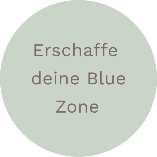 Kreis mit Text "Erschaffe deine Blue Zone" in Deutsch auf grauem Hintergrund.