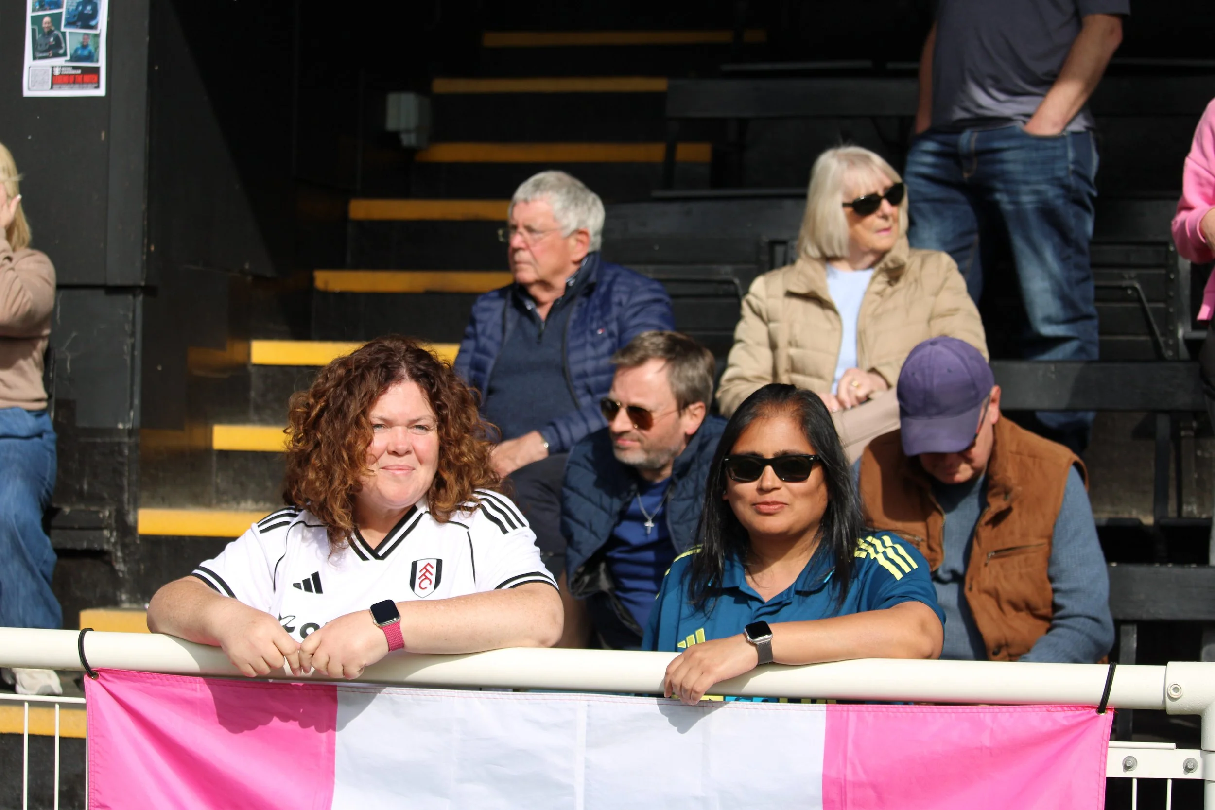 Two of the Fulham Lillies stand in front of their flag.
