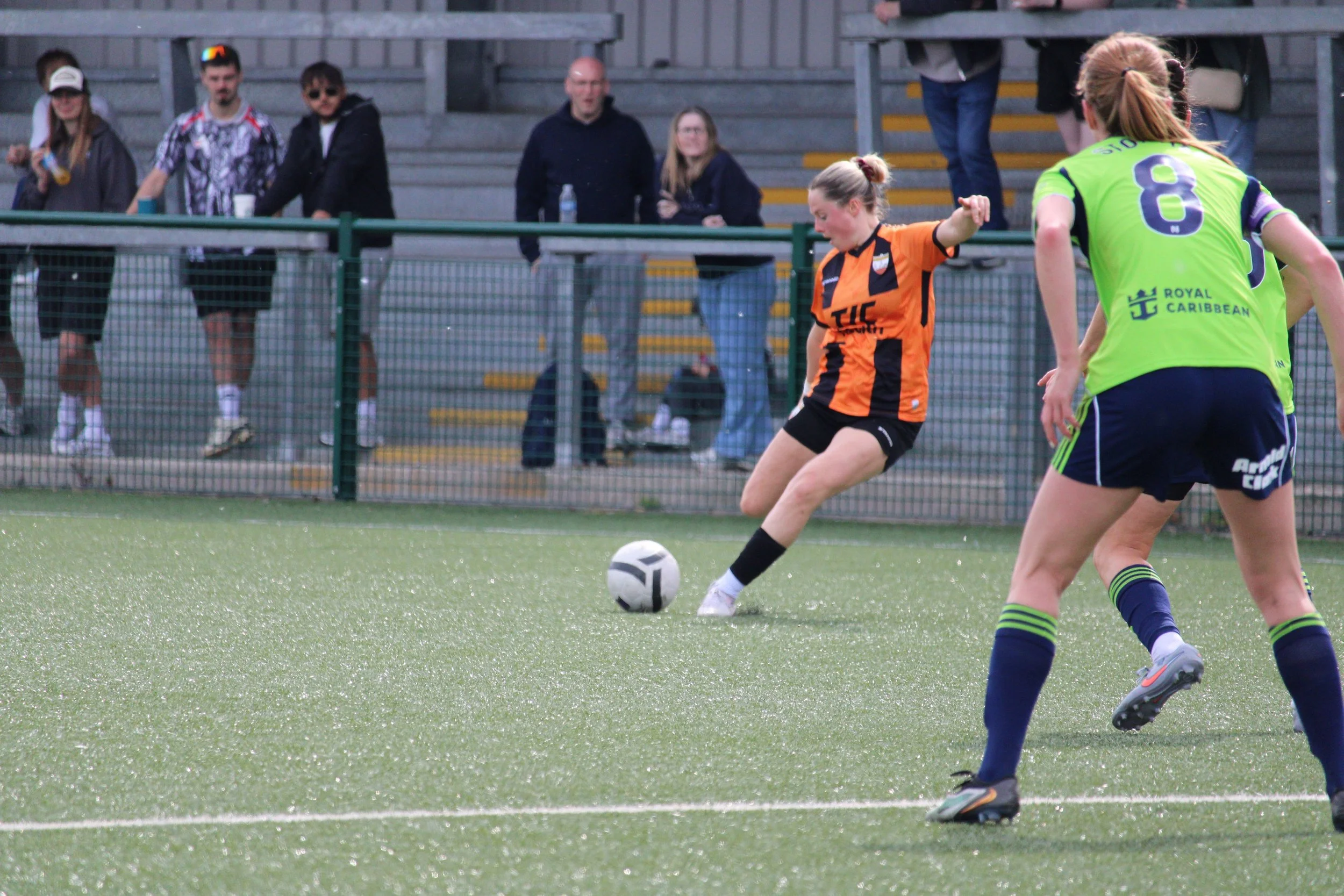 A London Bees player prepares to take a shot while Becky Stormer watches to see if she should intervene.