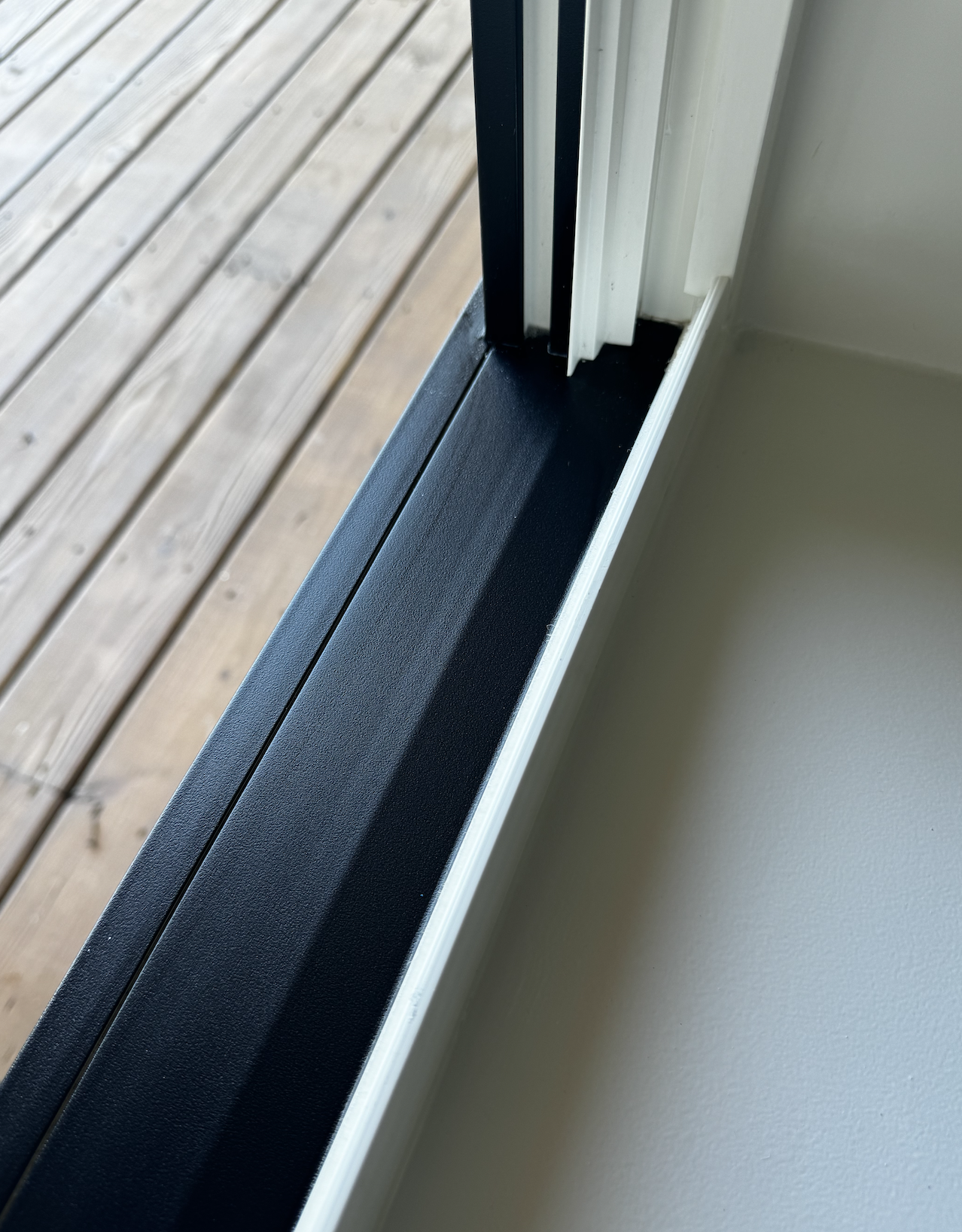 Close-up of a sliding glass door frame and a wooden deck outside.