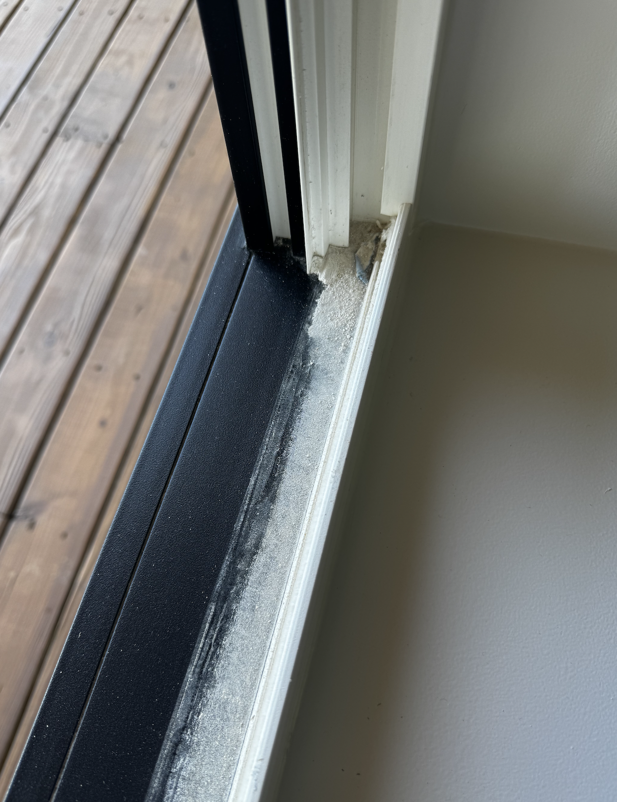 Close-up of a sliding glass door track with dust buildup inside.