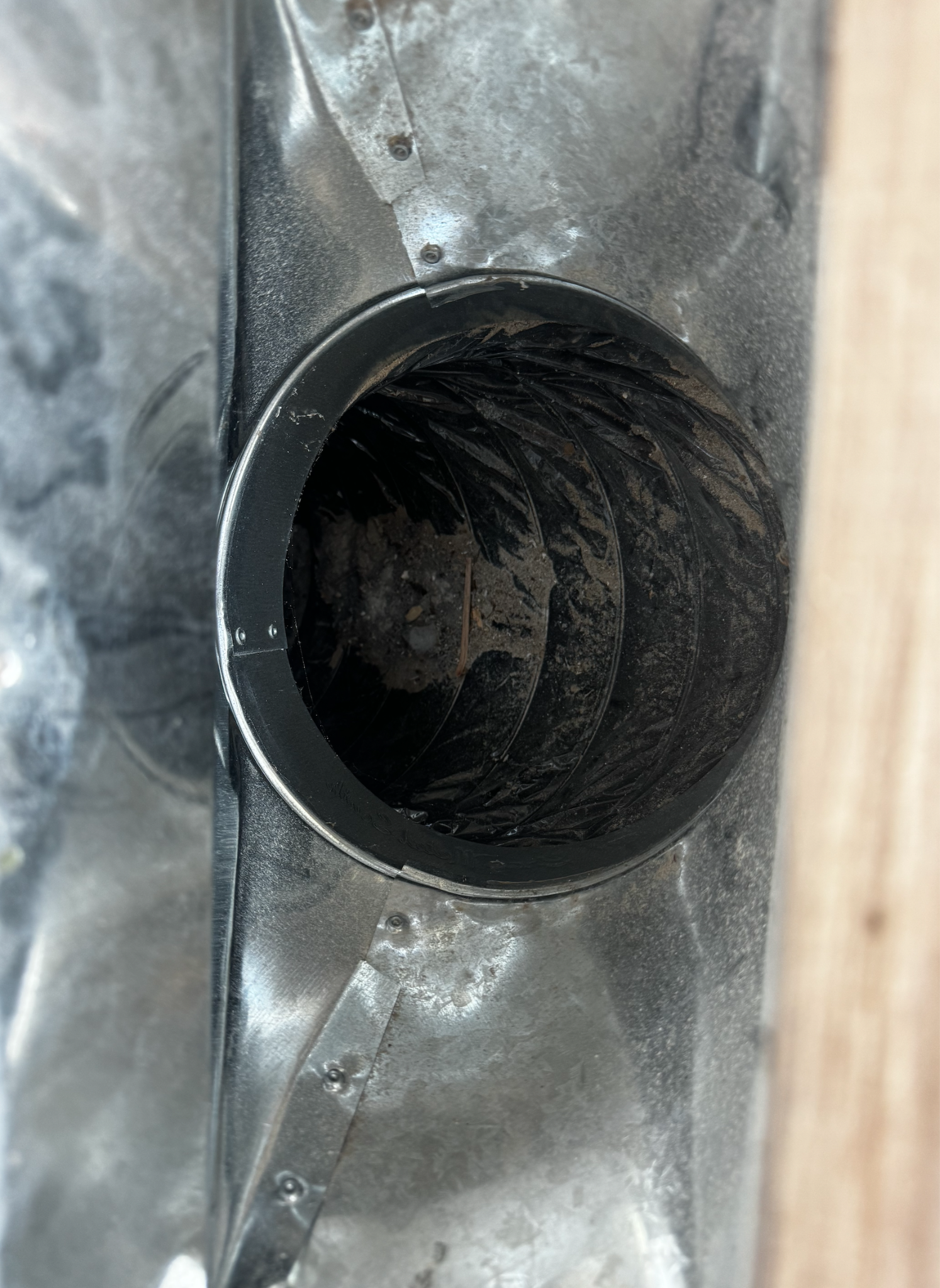 Close-up of a metallic industrial or mechanical component with a vent or opening, showing dust and wear.