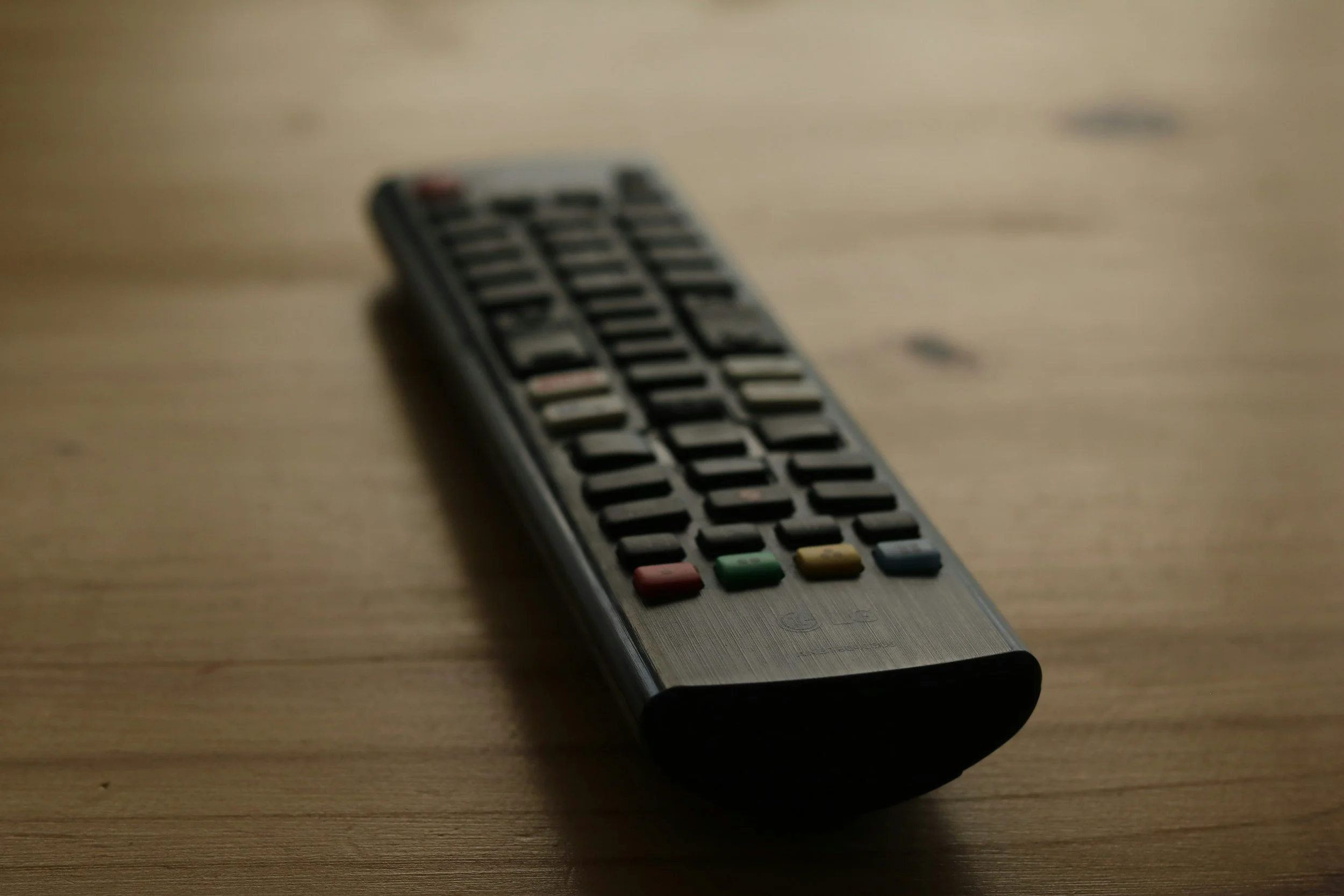 Remote control lying on a wooden surface.