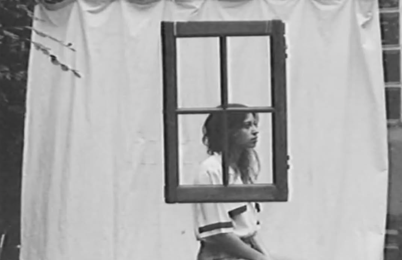 Artiste chanteuse et compositrice Alice et moi , Une jeune femme regarde à travers une fenêtre en bois suspendue au mur, avec des draps blancs en arrière-plan.