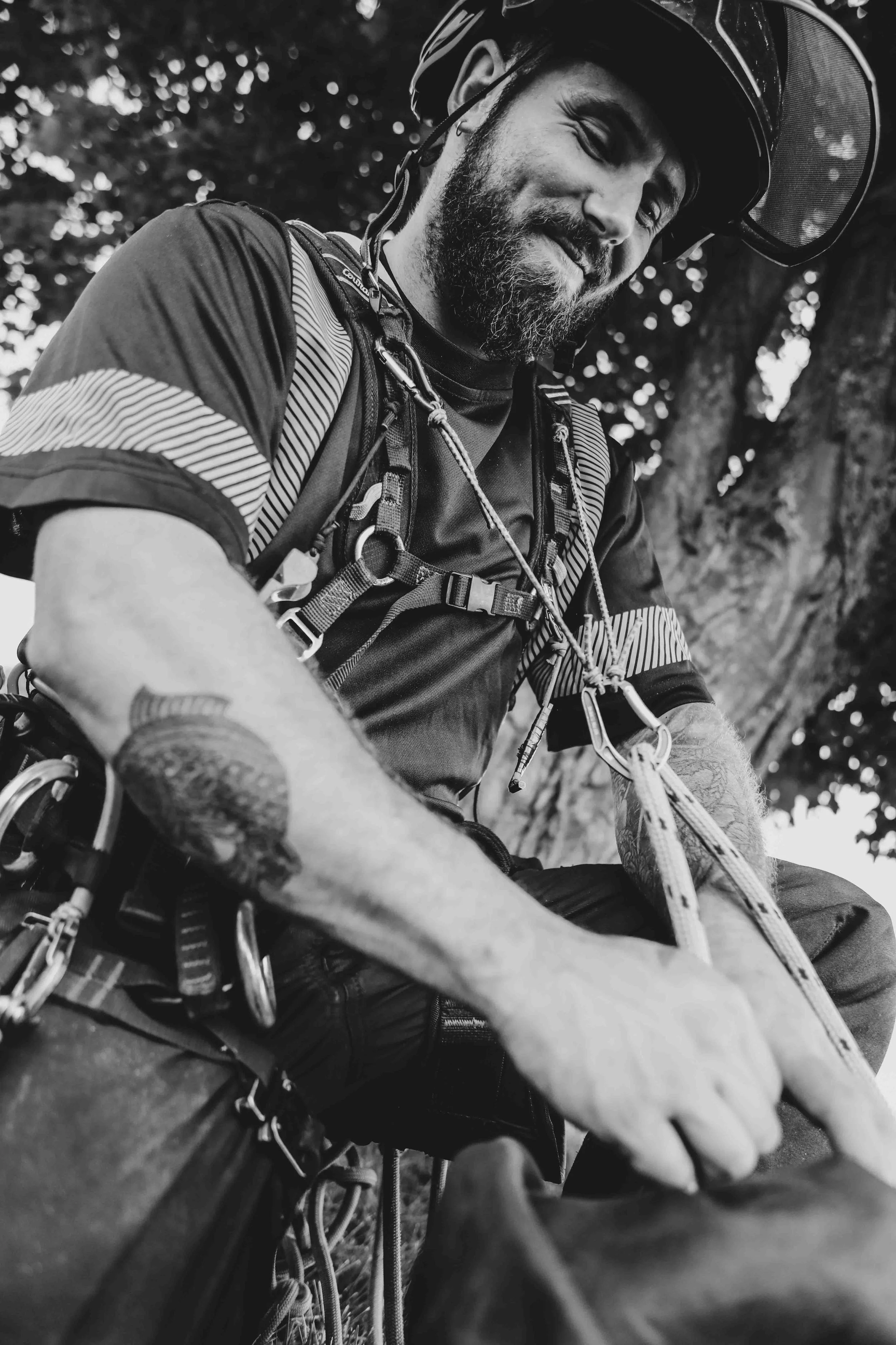 Un homme portant un casque, équipement d'escalade, souriant, dans un environnement naturel, probablement en train de faire de l'escalade ou de l'alpinisme.