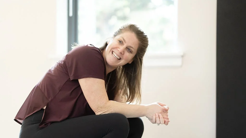 Dara Galasso smiling while sitting near a window in the studio.