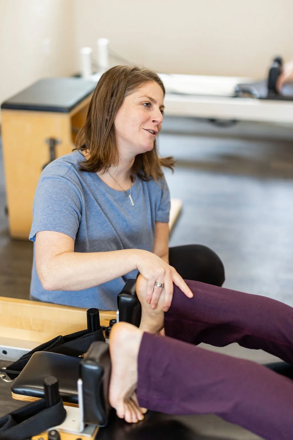 Instructor assisting a client with a leg stretch during a Pilates session.