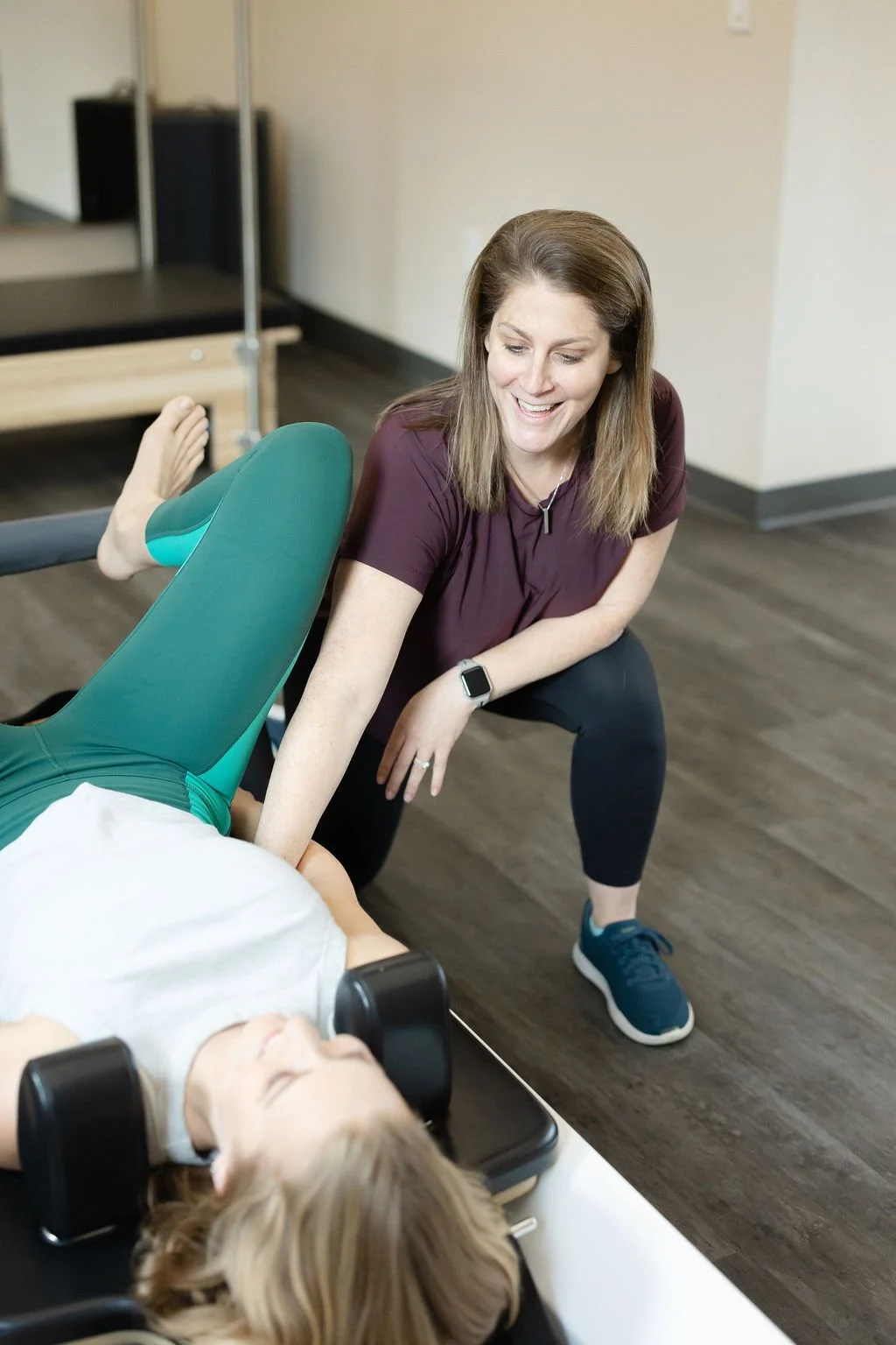 Instructor assisting a client with a stretch on a reformer.