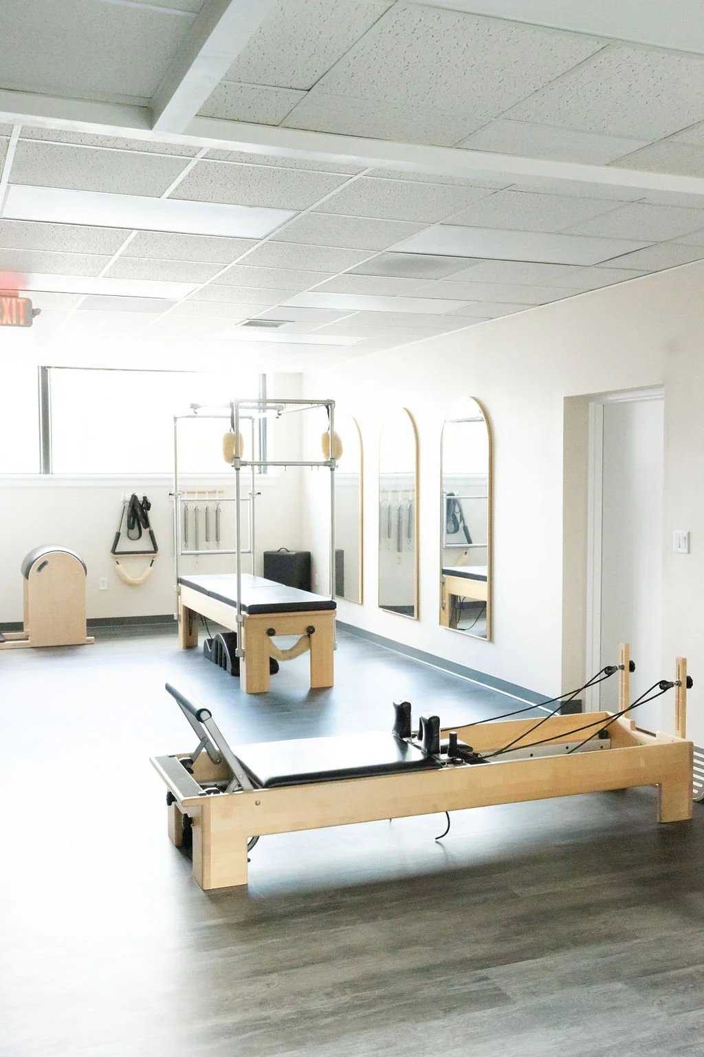 Pilates Plus studio with a reformer, mirrored walls, and natural light