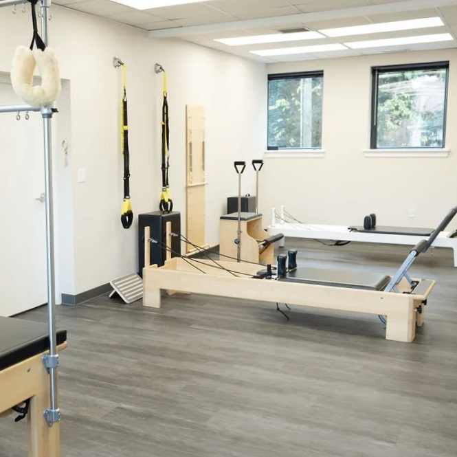 Pilates studio with reformers, resistance bands, and suspension straps