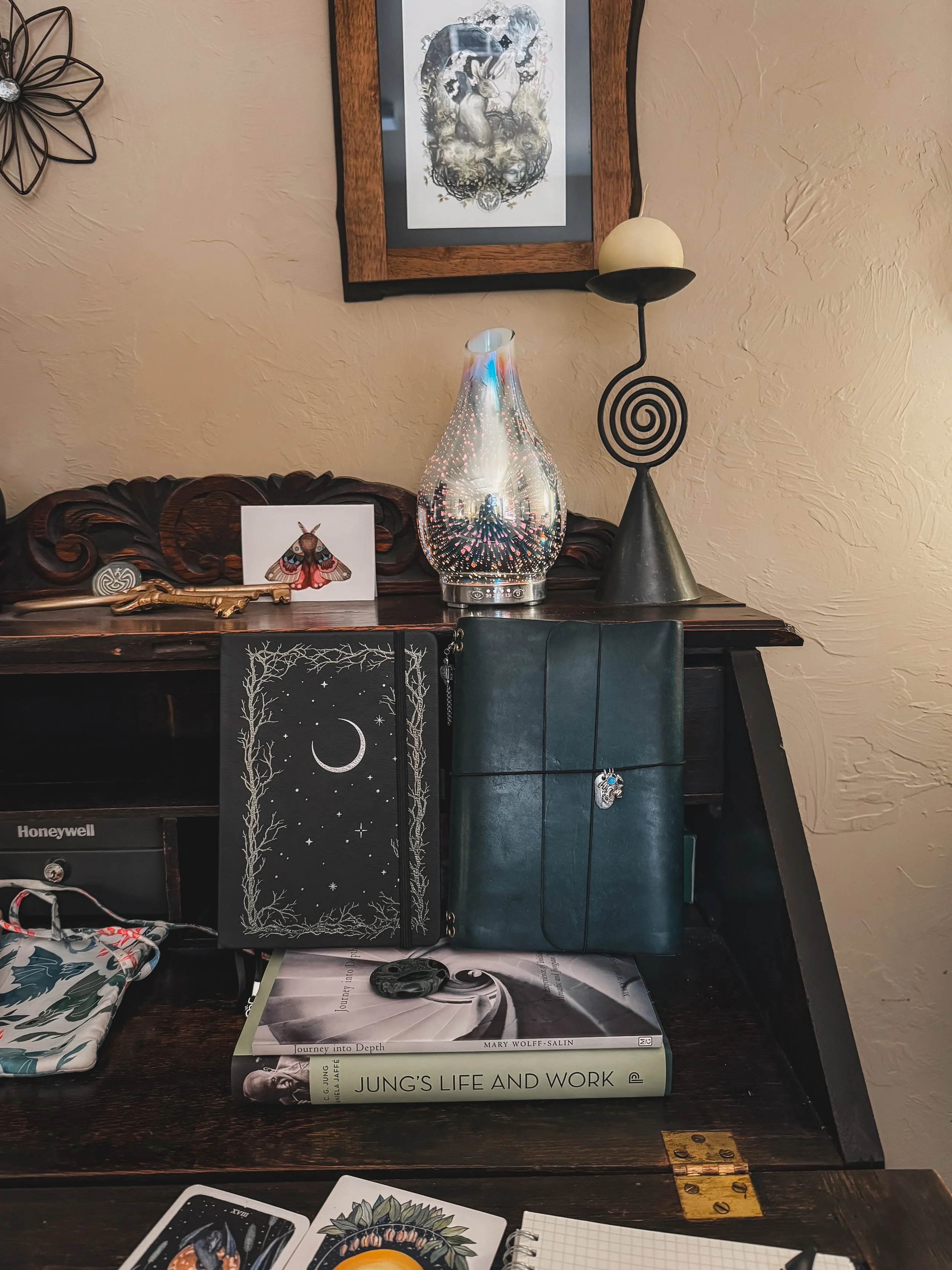 Wooden desk with journals, Jungian texts, symbolic artwork, and contemplative objects reflecting a depth-oriented psychotherapy practice.