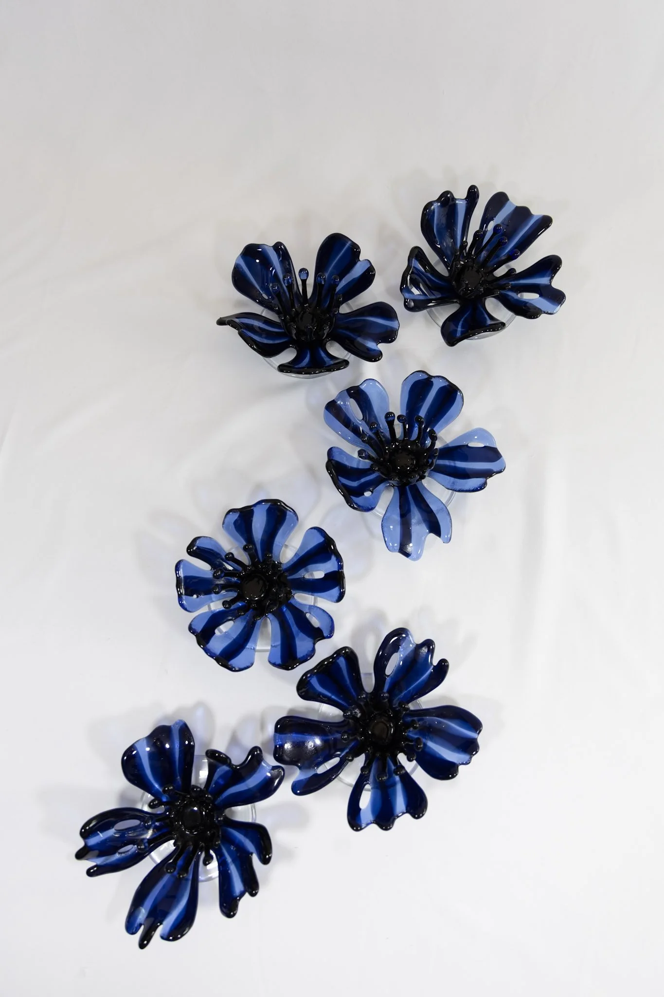 Collection of blue and black glass flowers with striped patterns on a white background.