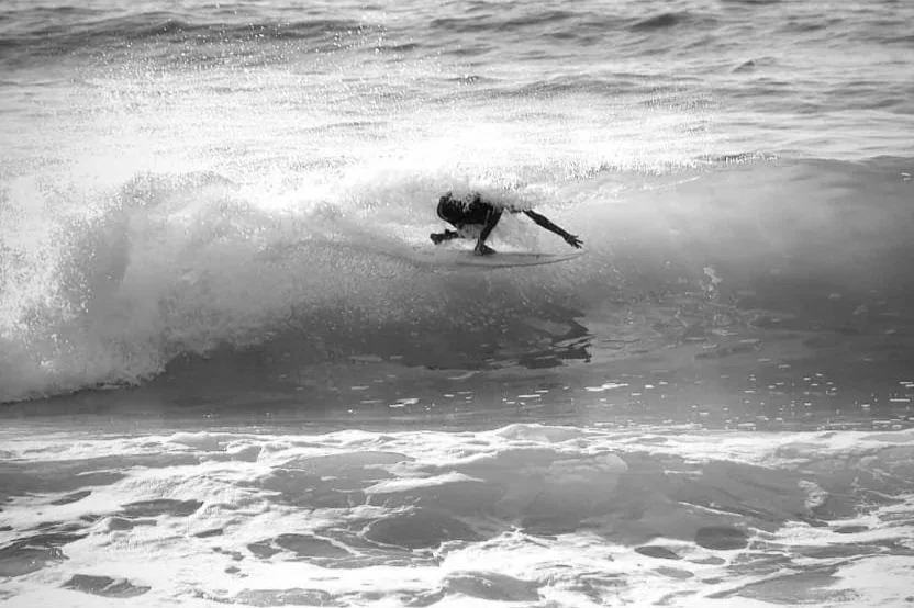 A person surfing on a wave in the ocean, black and white photo.