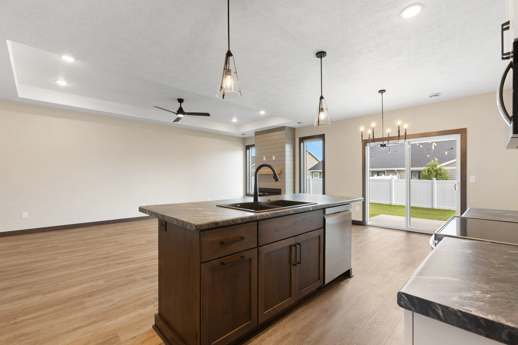 Open-concept kitchen with island, wood flooring, large windows, and a ceiling fan.