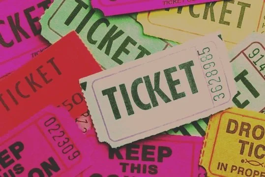A collection of colorful tickets, including green, pink, red, yellow, and white, with various texts and barcodes.