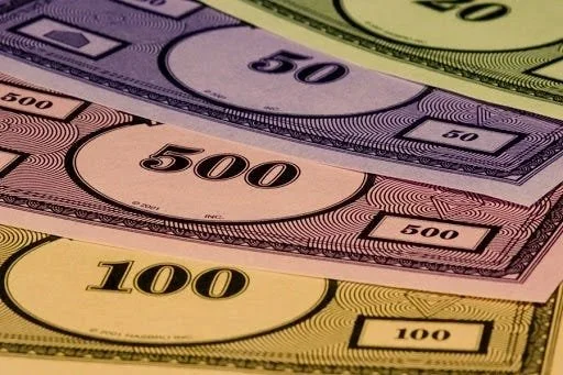 Close-up of various colorful play money bills with denominations of 100, 500, and 50.