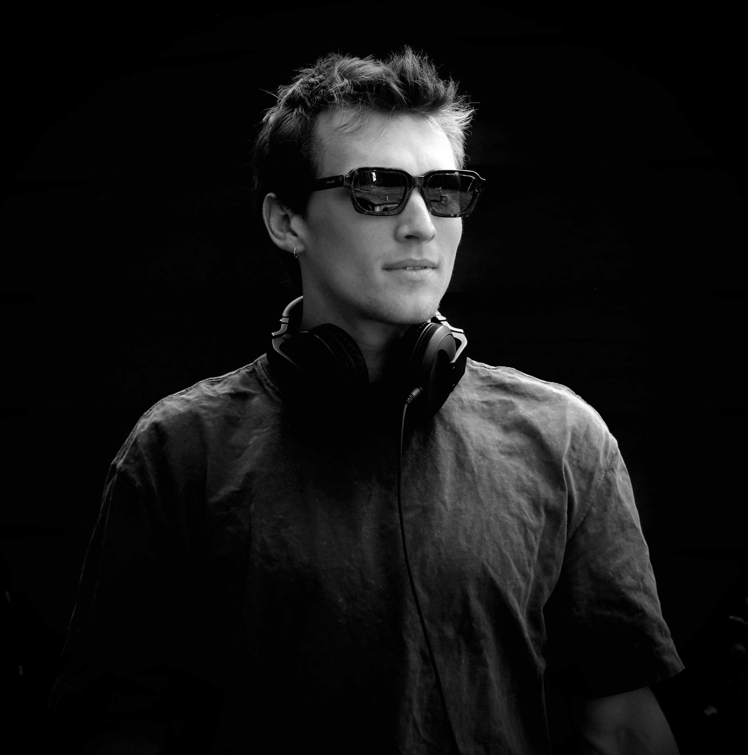 A person wearing sunglasses with a dark background.