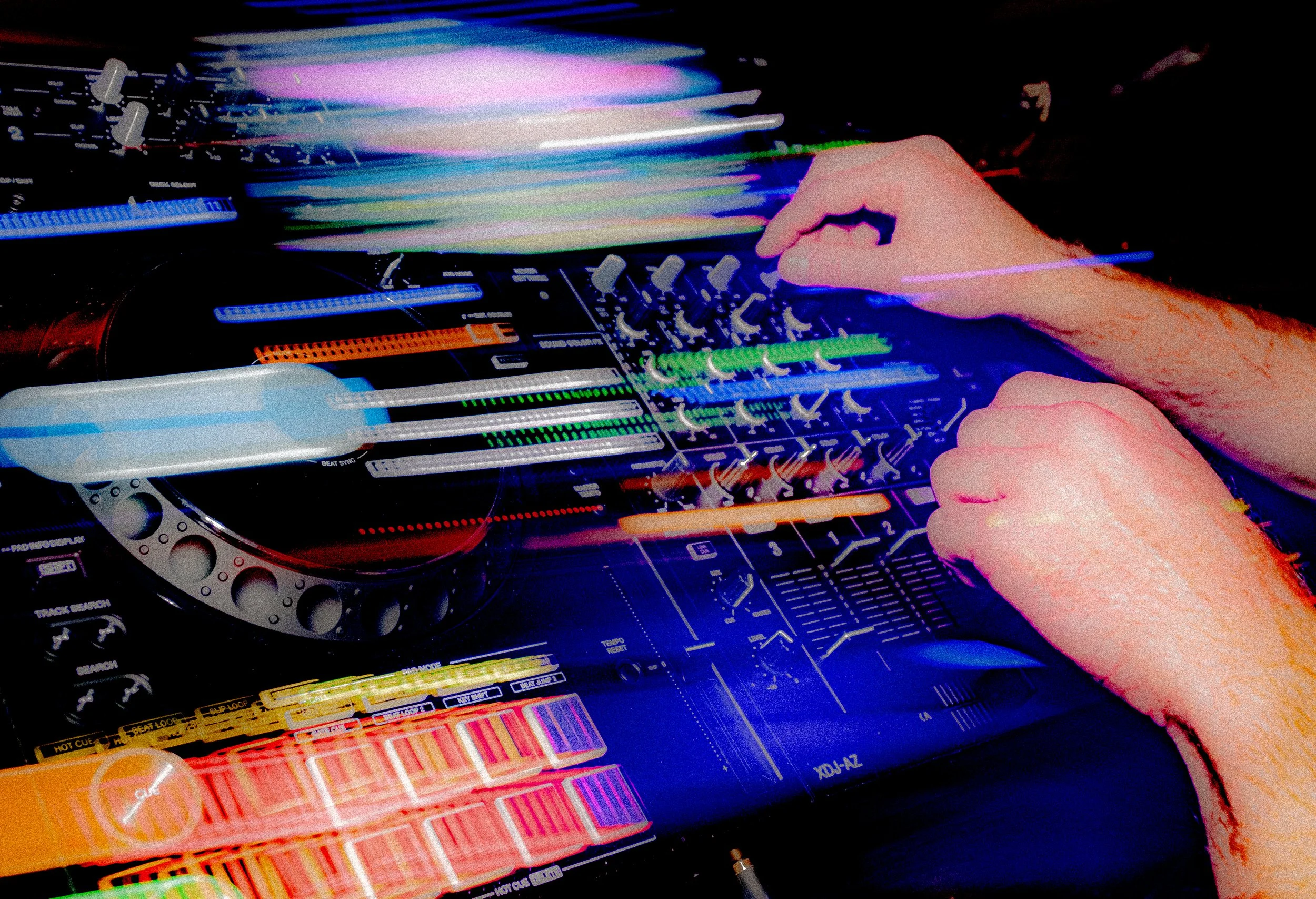A DJ mixing music on a turntable with colorful lights and sound equipment.