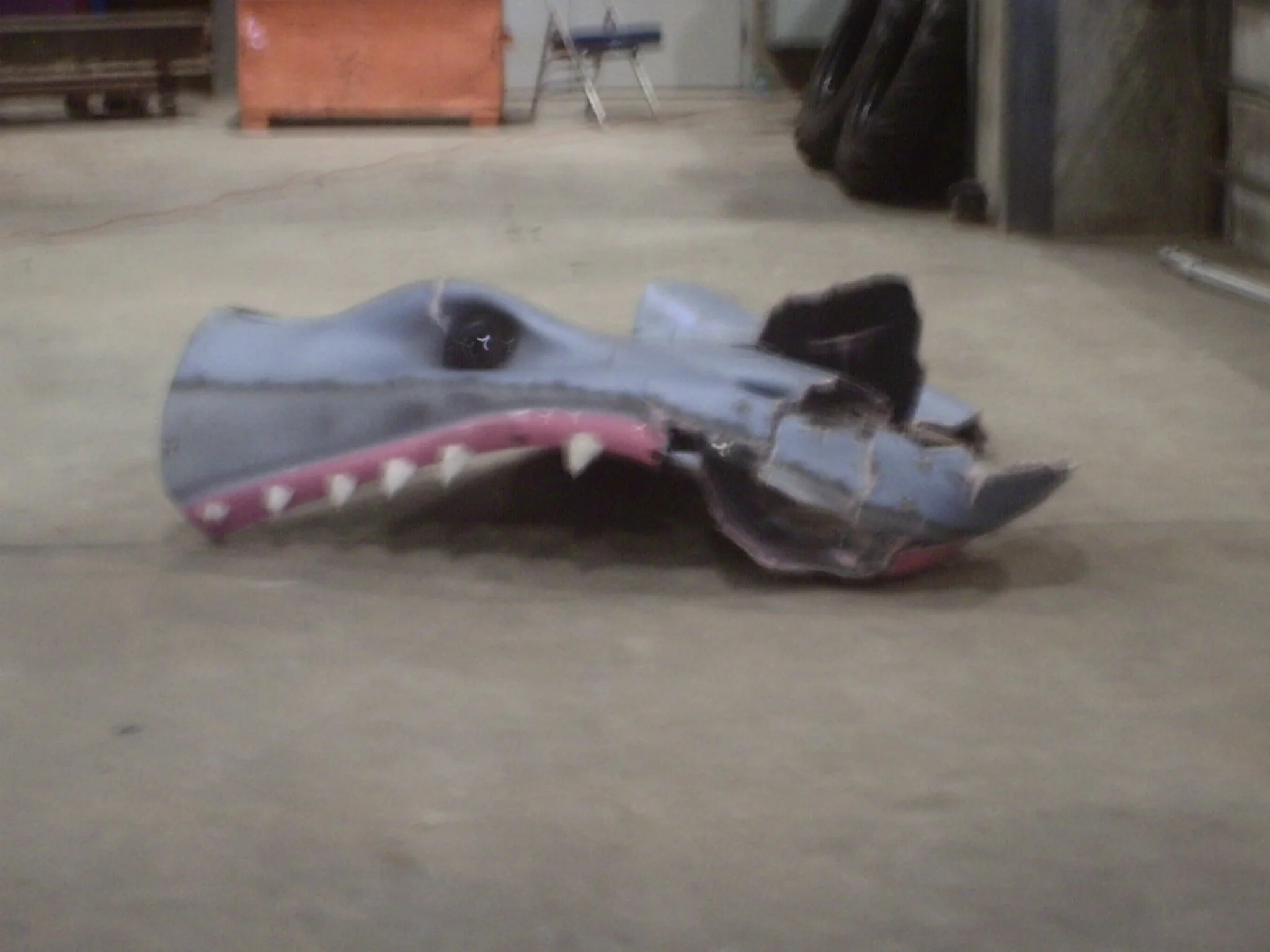 A broken shark-shaped object on a garage floor with various items in the background.