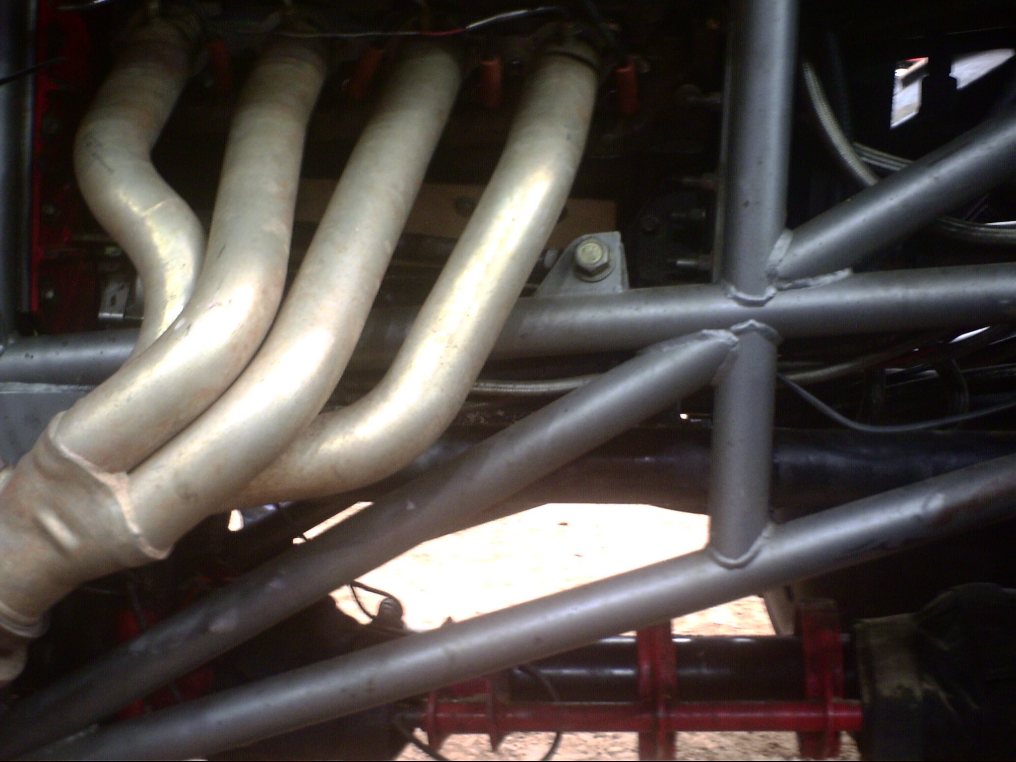 Close-up view of a series of metallic pipes arranged in parallel, connected to a mechanical or industrial system with visible bolts and a structural frame.
