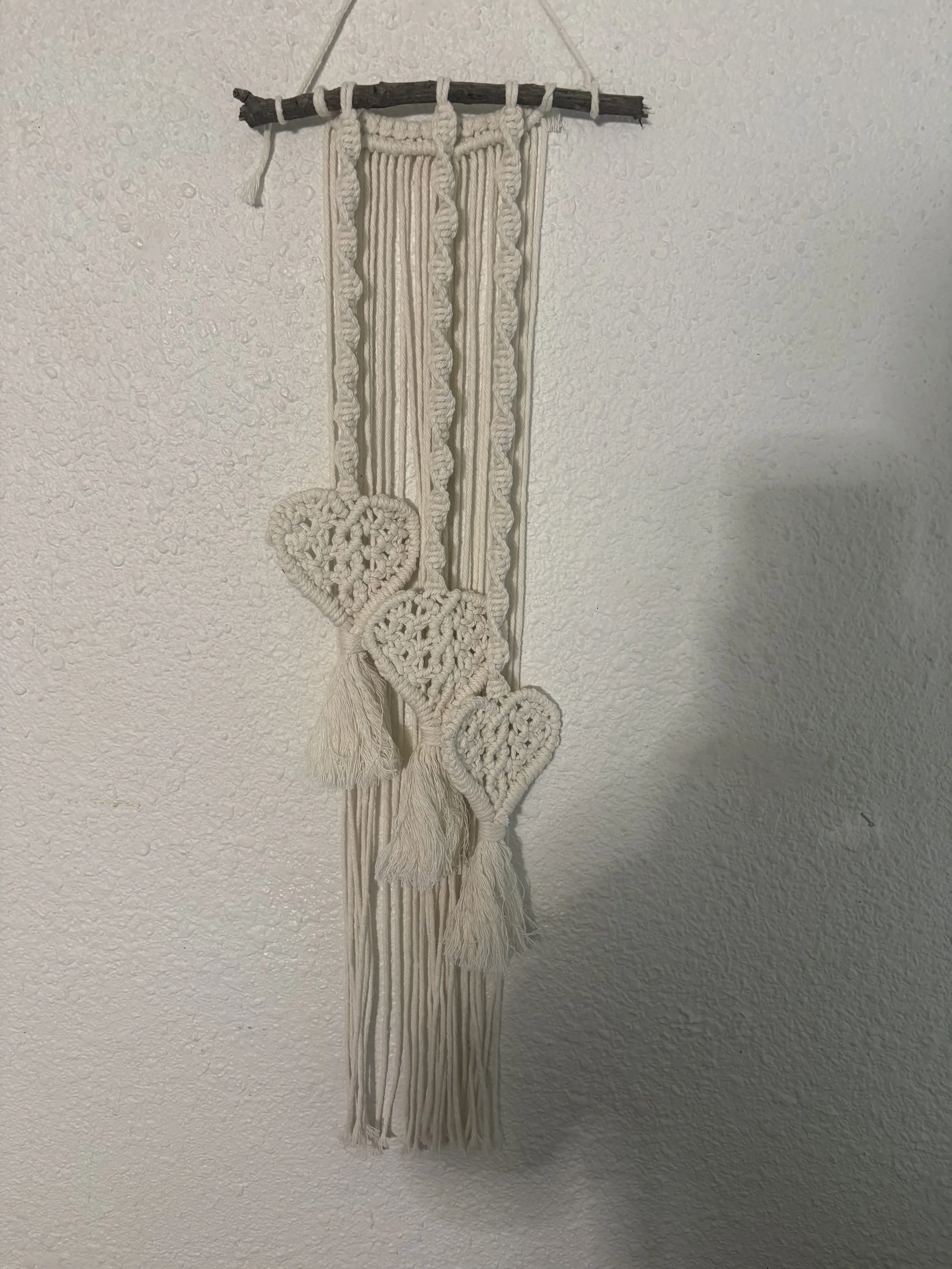 Heartstrings
(6" x 28")
Three knotted hearts suspended among flowing cords create a playful yet elegant design. Soft textures and gentle movement make this piece a charming reminder of connection, kindness, and love.
$60.00