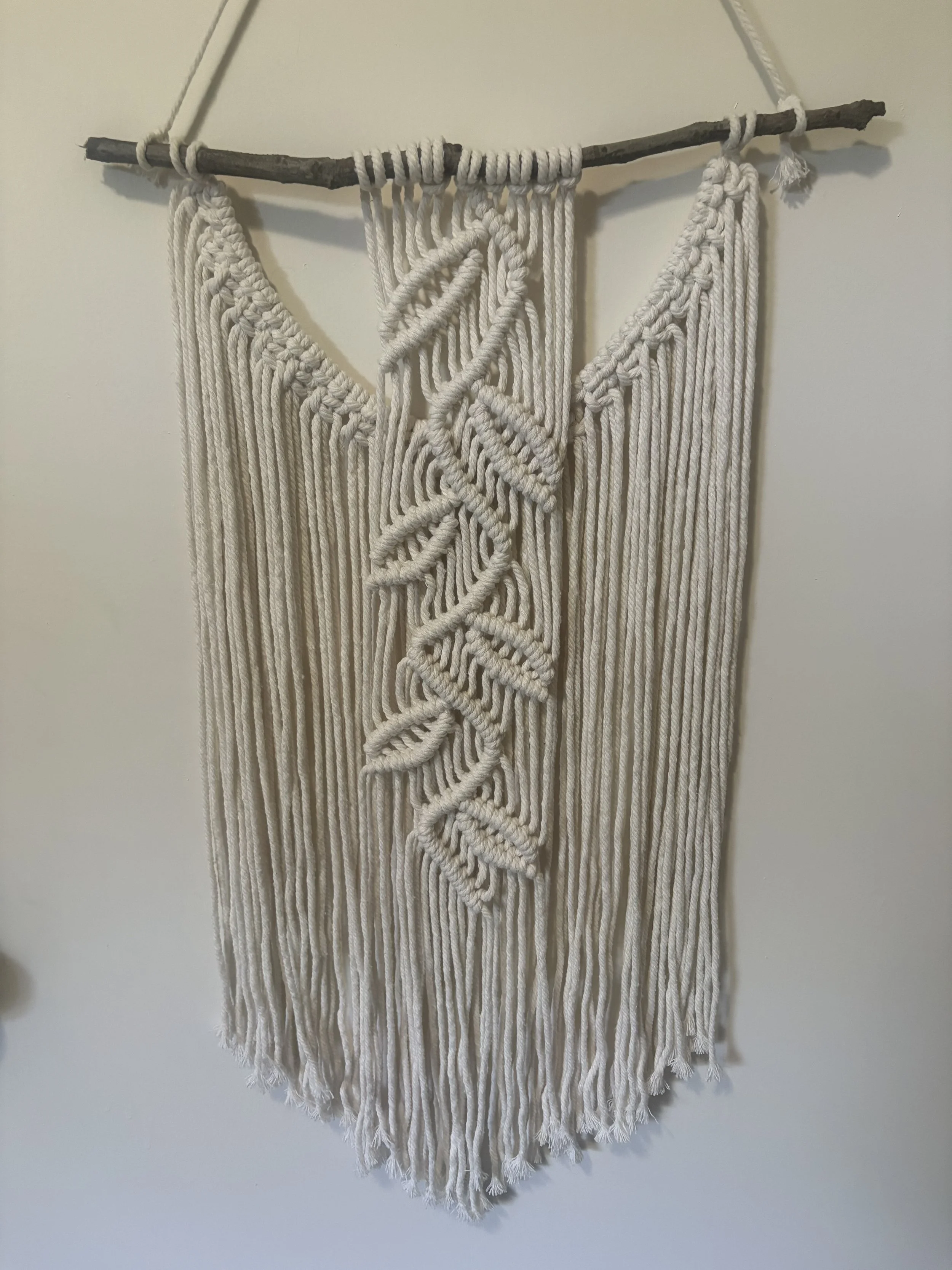 Forest Fronds 
(13" x 27")
Inspired by woodland foliage, this wall hanging features layered leaf motifs framed by flowing fringe. Its organic design brings texture, movement, and a touch of nature indoors.
$75.00