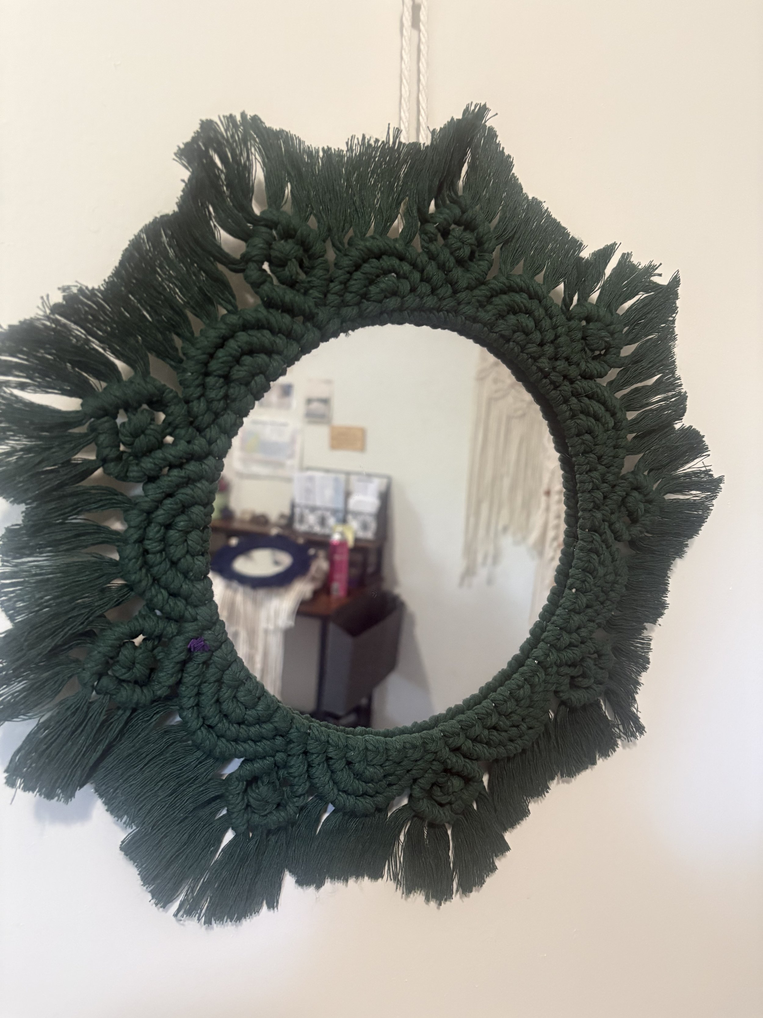 Forest Bloom Mirror
(15" x 15")
Rich green cord woven into a blooming floral design surrounds this handcrafted mirror. Inspired by mossy forests and wild gardens, it brings texture, warmth, and a touch of nature indoors.
$80.00