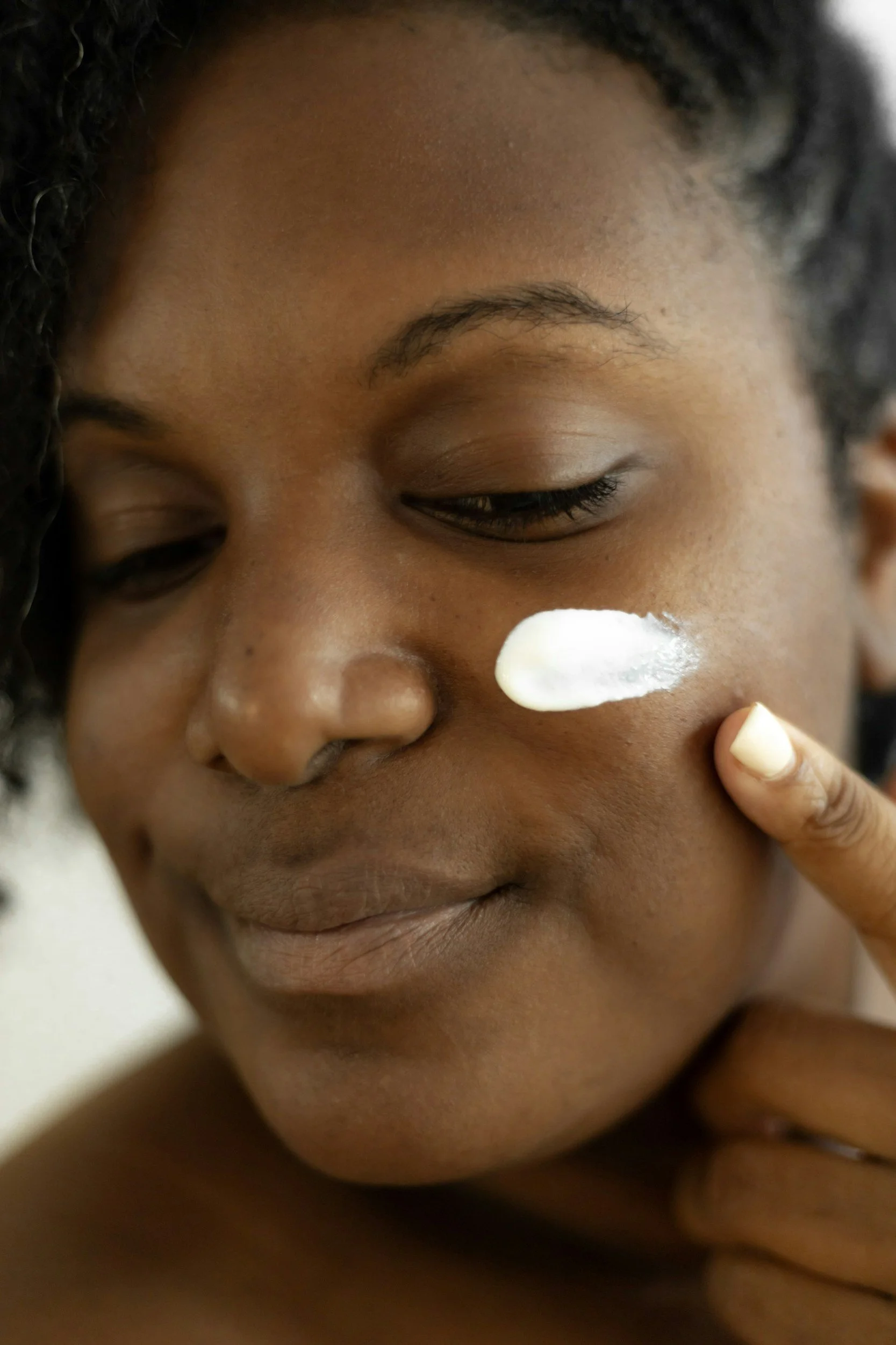 Woman applying facial cream as part of her skincare routine