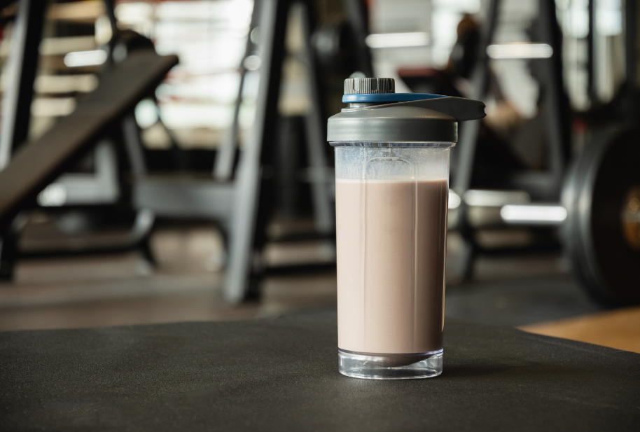 Protein shake beside workout equipment in a gym