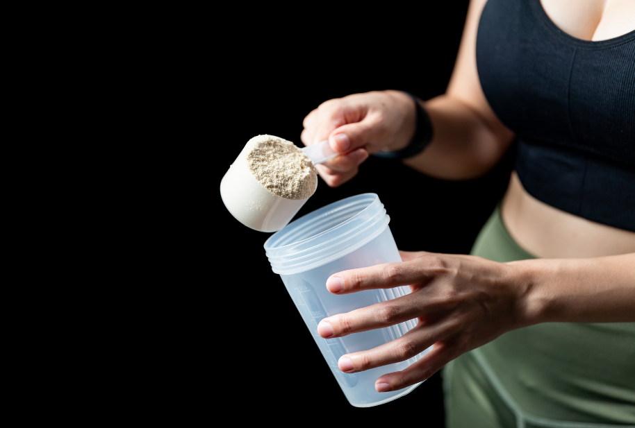 Person scooping protein powder into a shaker cup