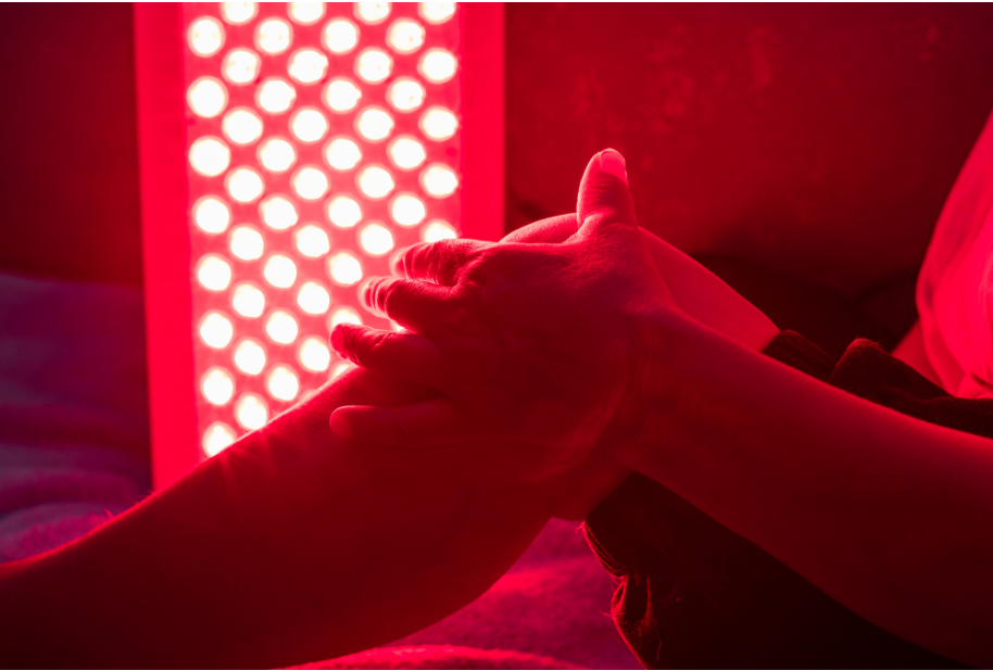 Hands exposed to a red light therapy panel