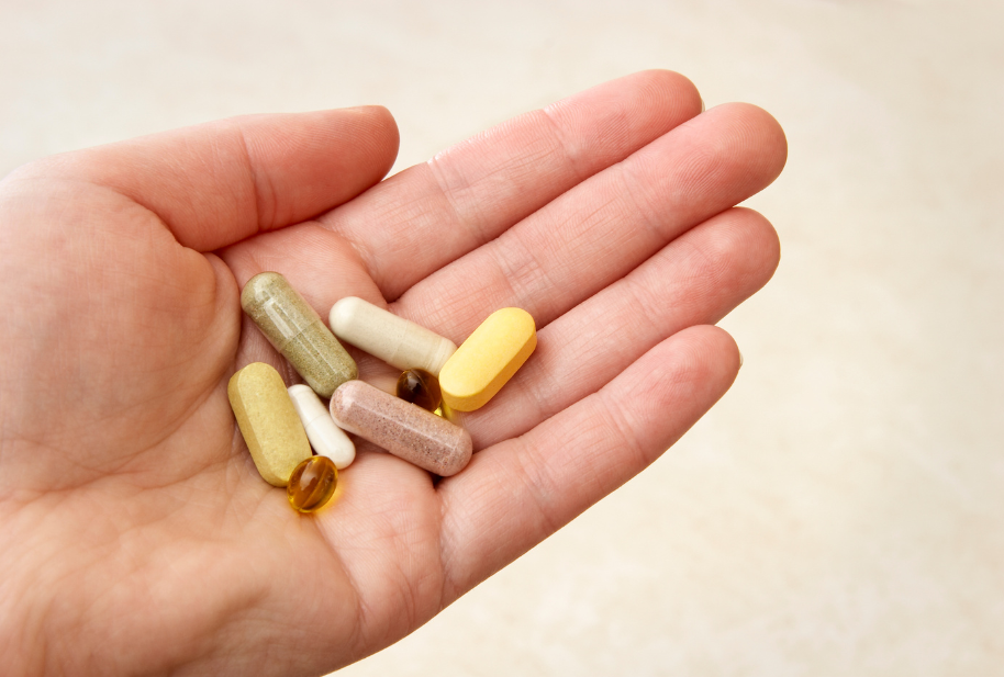 Assorted daily wellness supplements in a person's hand