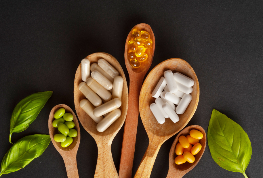 Assorted vitamins and supplements arranged in wooden spoons