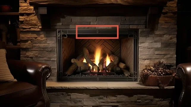 Living room fireplace with a fire burning, surrounded by stone, with two leather armchairs on either side.