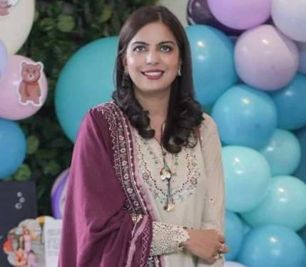 A woman in traditional attire standing in front of colorful balloons, smiling.
