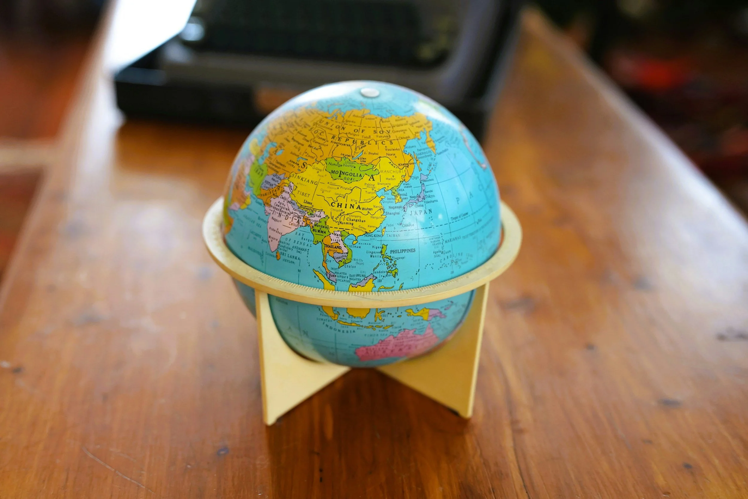 A small globe on a wooden table showing parts of Asia and surrounding regions.