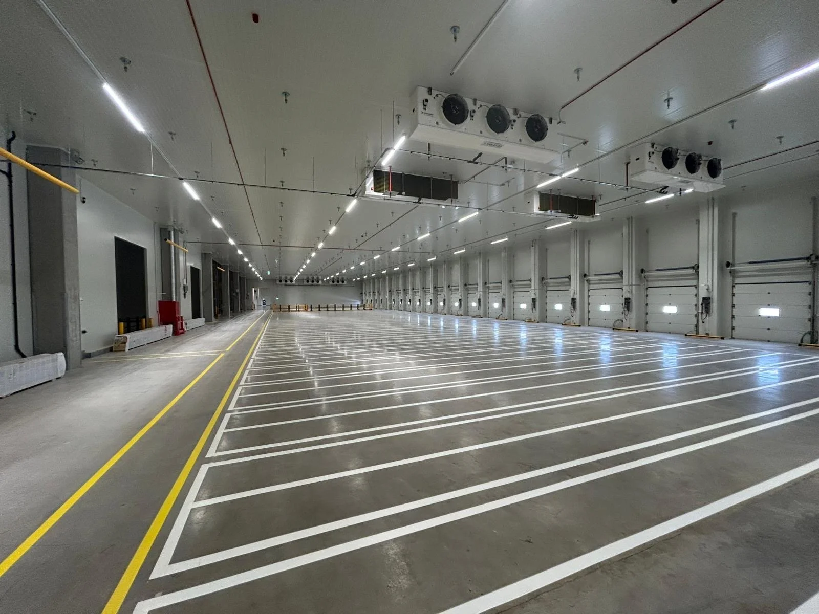 Grote lege logistieke hal met gestreepte parkeerplaatsen en sluipverkeer-lijnen.