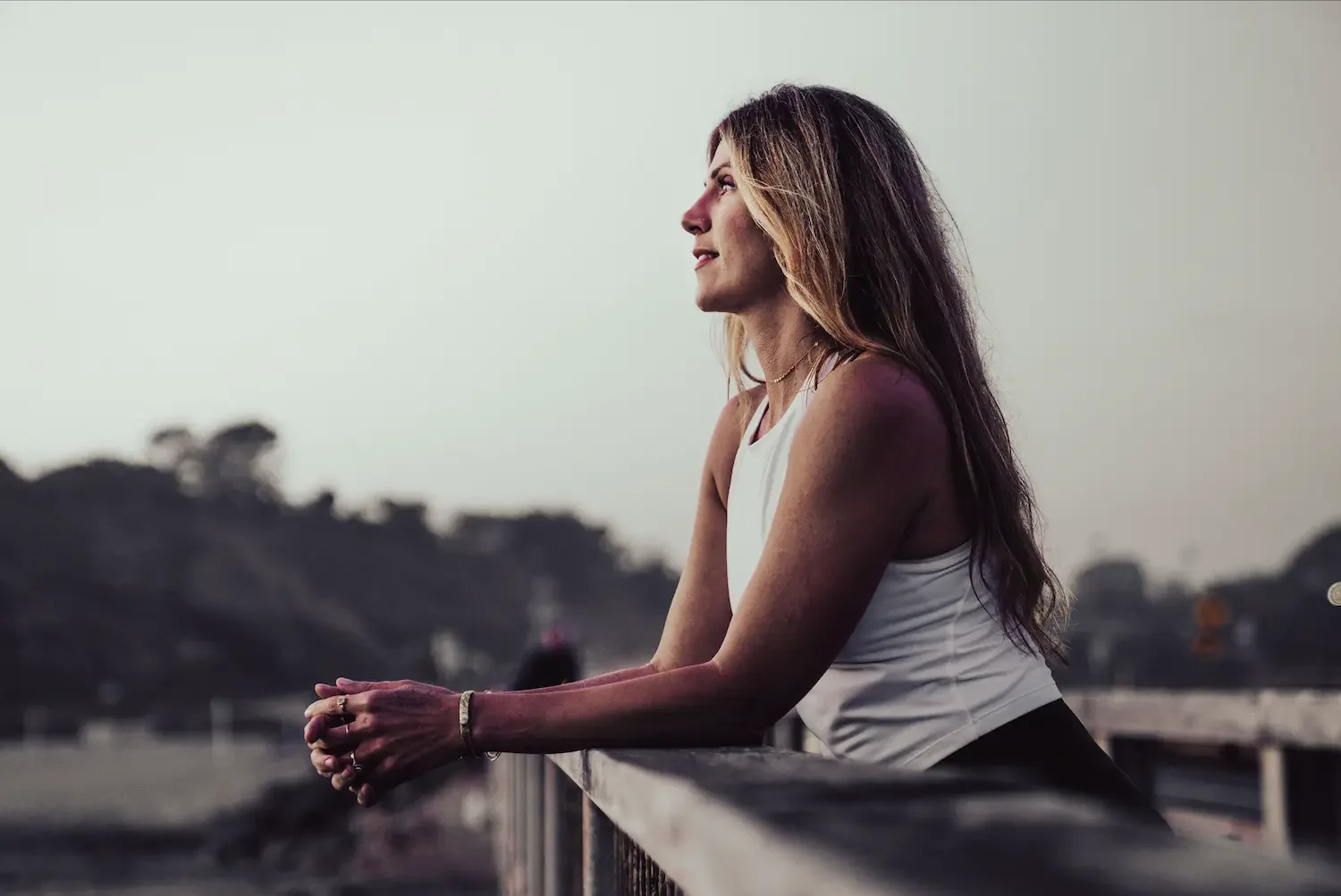 Woman leaning on a railing, looking out at the horizon in golden hour light