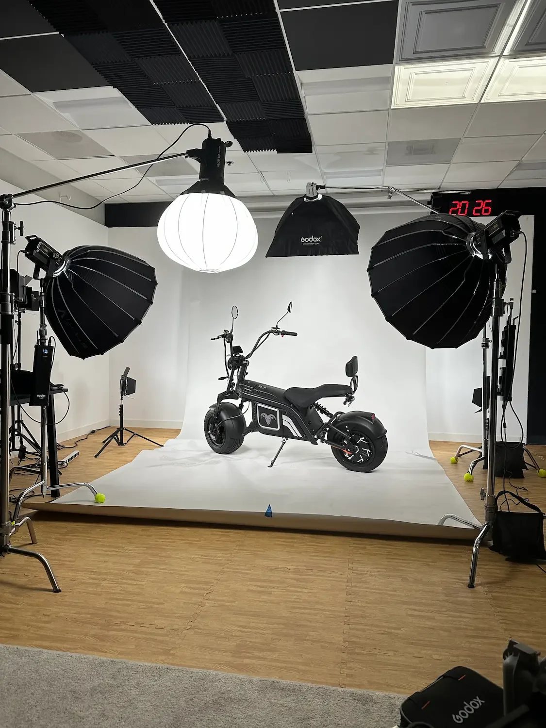Photography studio with professional lighting equipment and a black electric bike on a white backdrop.