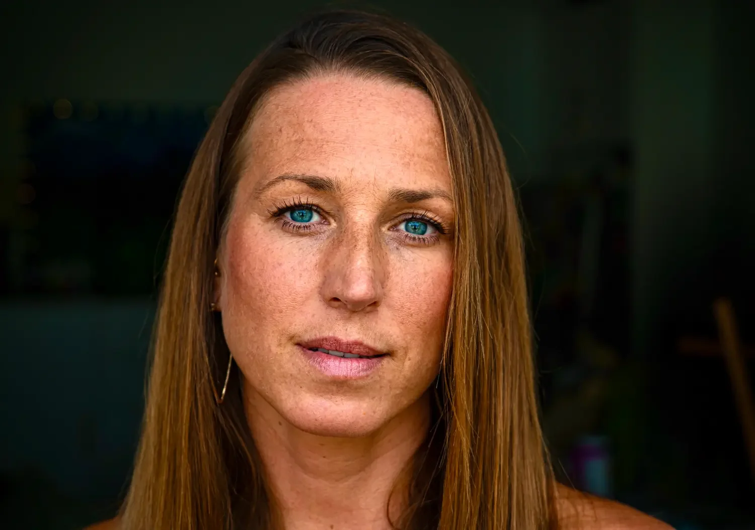 Close-up headshot of a woman against a dark background