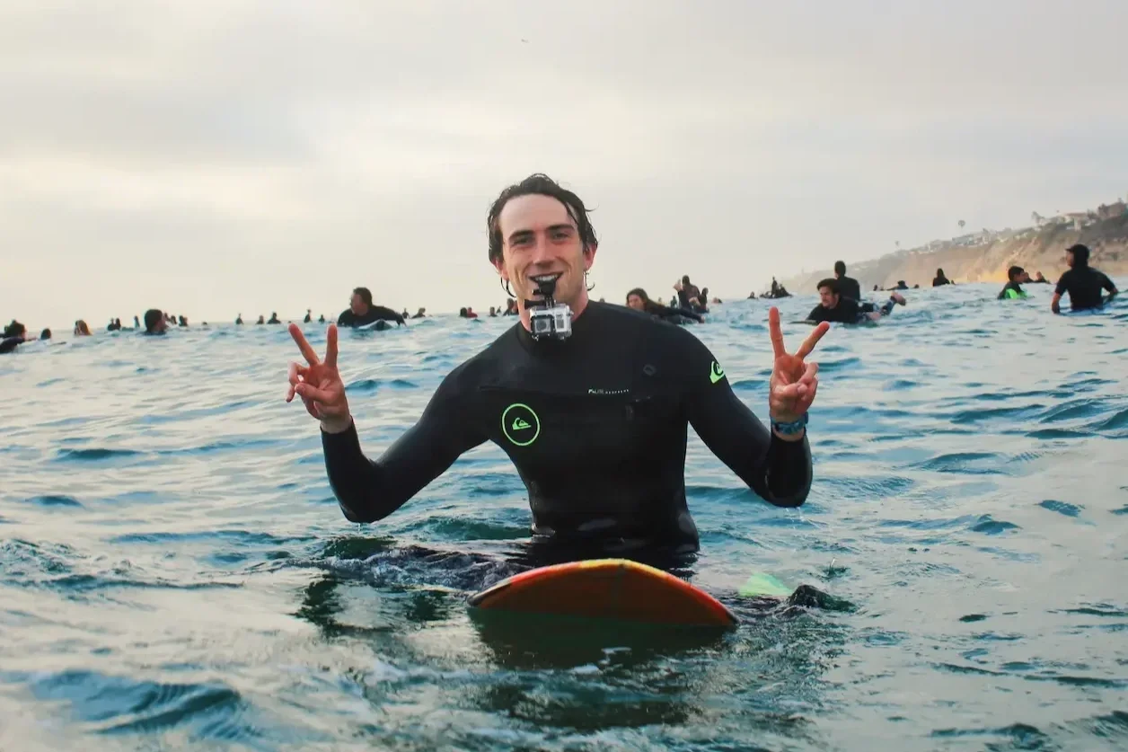 Jack Lajoie, San Diego photographer, giving a peace sign while surfing with a GoPro mounted on his chest