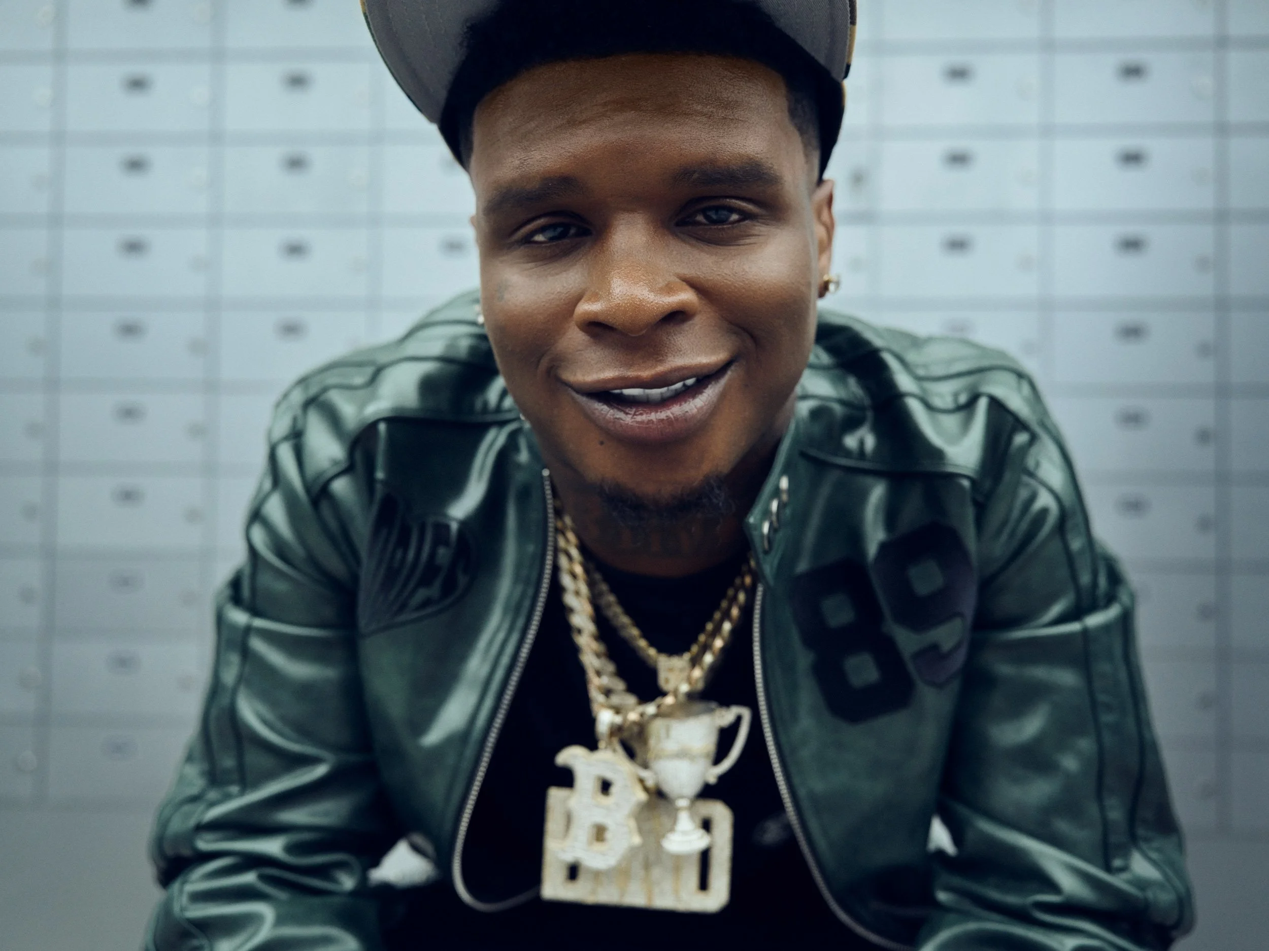 HoodTrophy Bino seated against metal lockers during a South Los Angeles music production