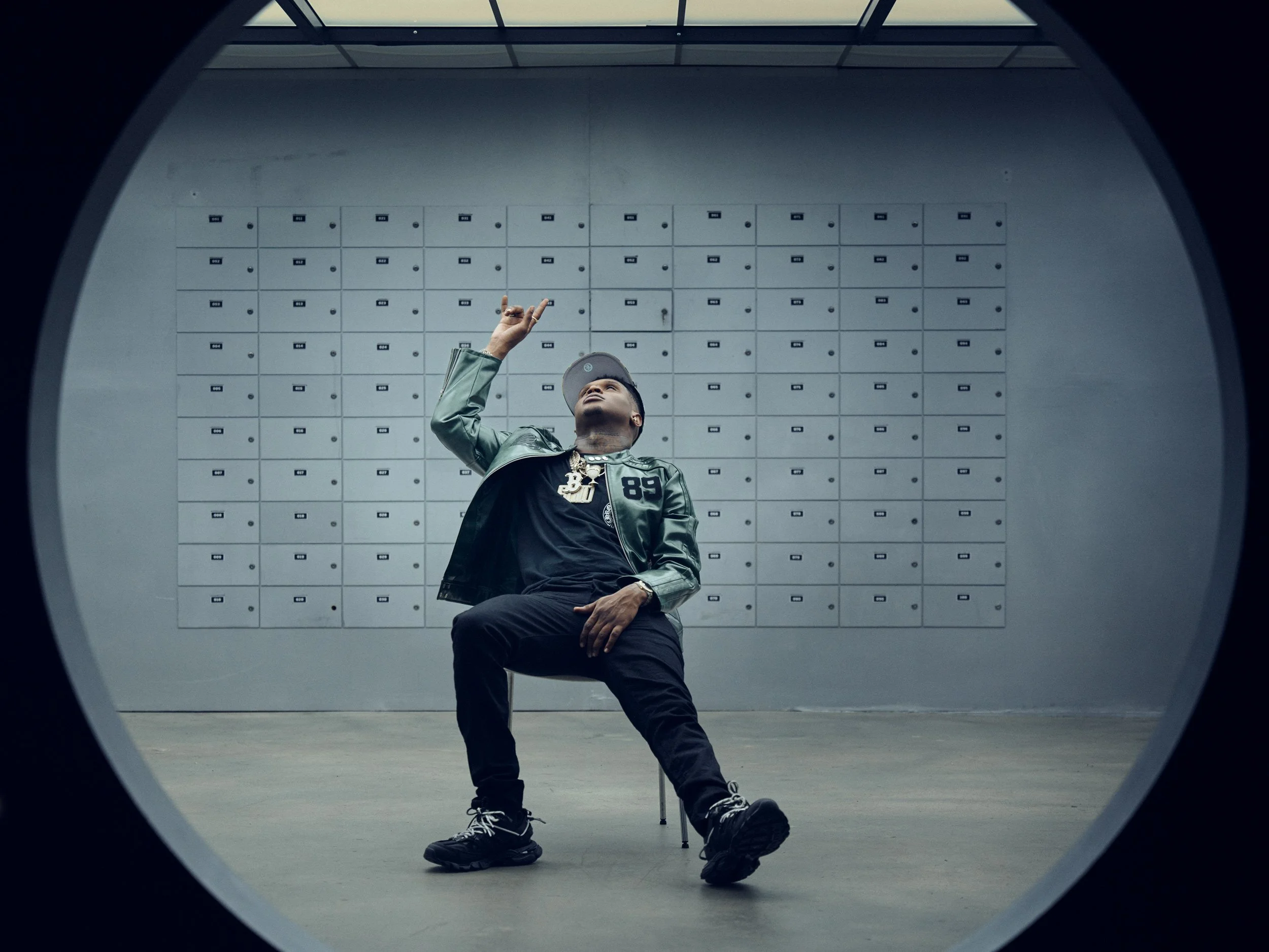 Wide environmental portrait of HoodTrophy Bino beneath a circular architectural frame in Los Angeles
