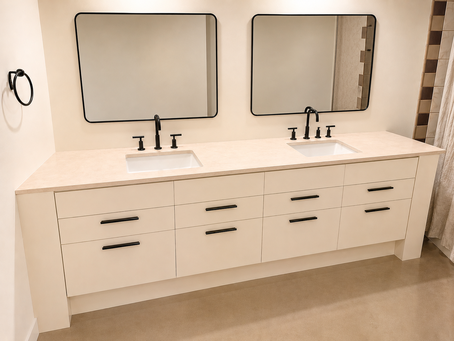 Double bathroom vanity with two rectangular mirrors, beige countertop, and black faucets and handles, against a light-colored wall.