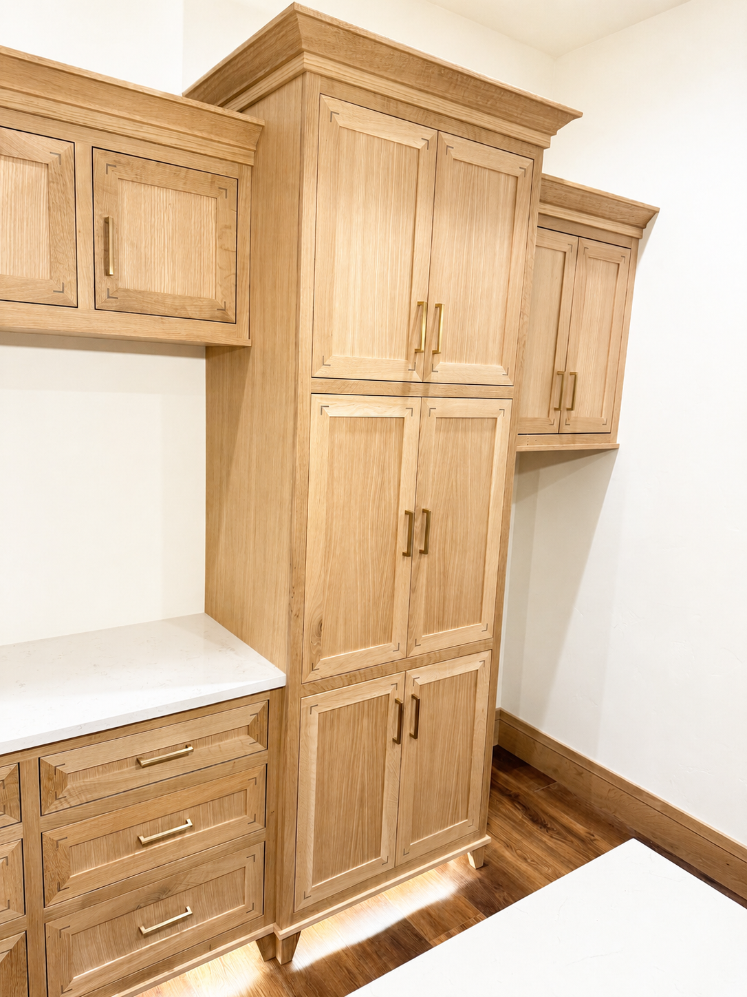 Wooden kitchen cabinets with brass handles and a white countertop.