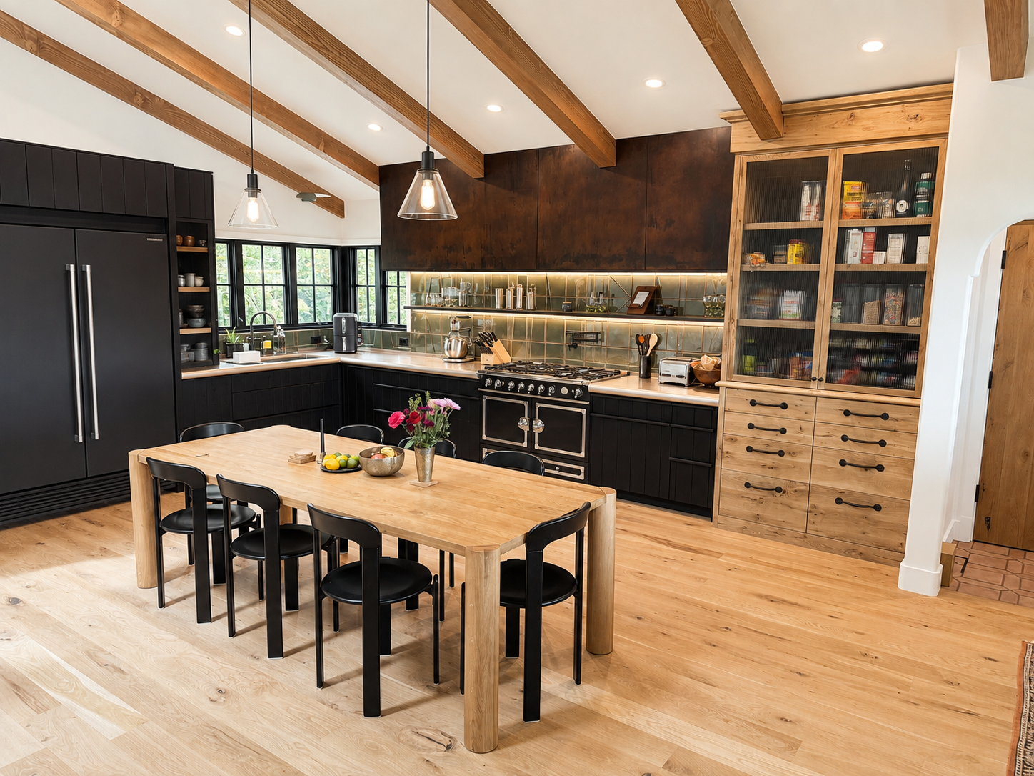 Modern kitchen with wooden ceiling beams, black cabinets, a wooden dining table with six black chairs, and a green tile backsplash. There are pendant lights hanging above the table, and a window with black frames over the sink. The kitchen has open s