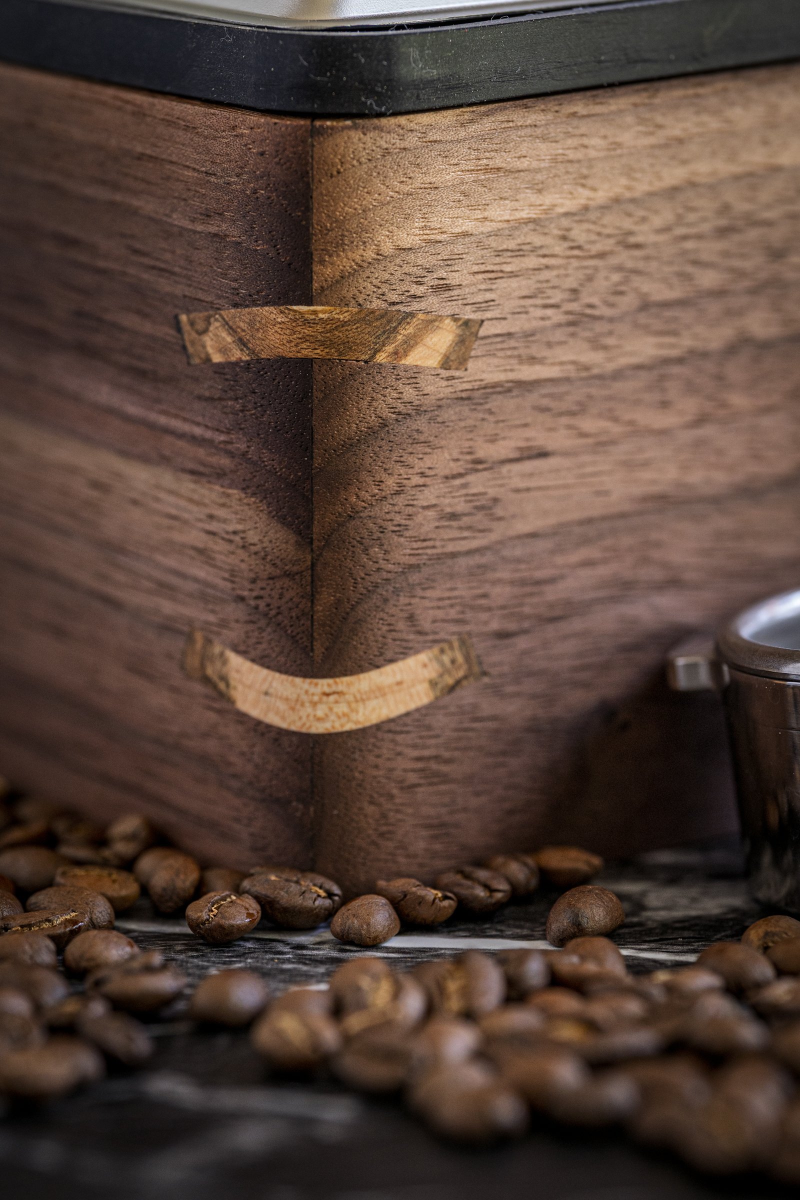Close-up of a wooden espresso knock box with coffee beans scattered at the base.