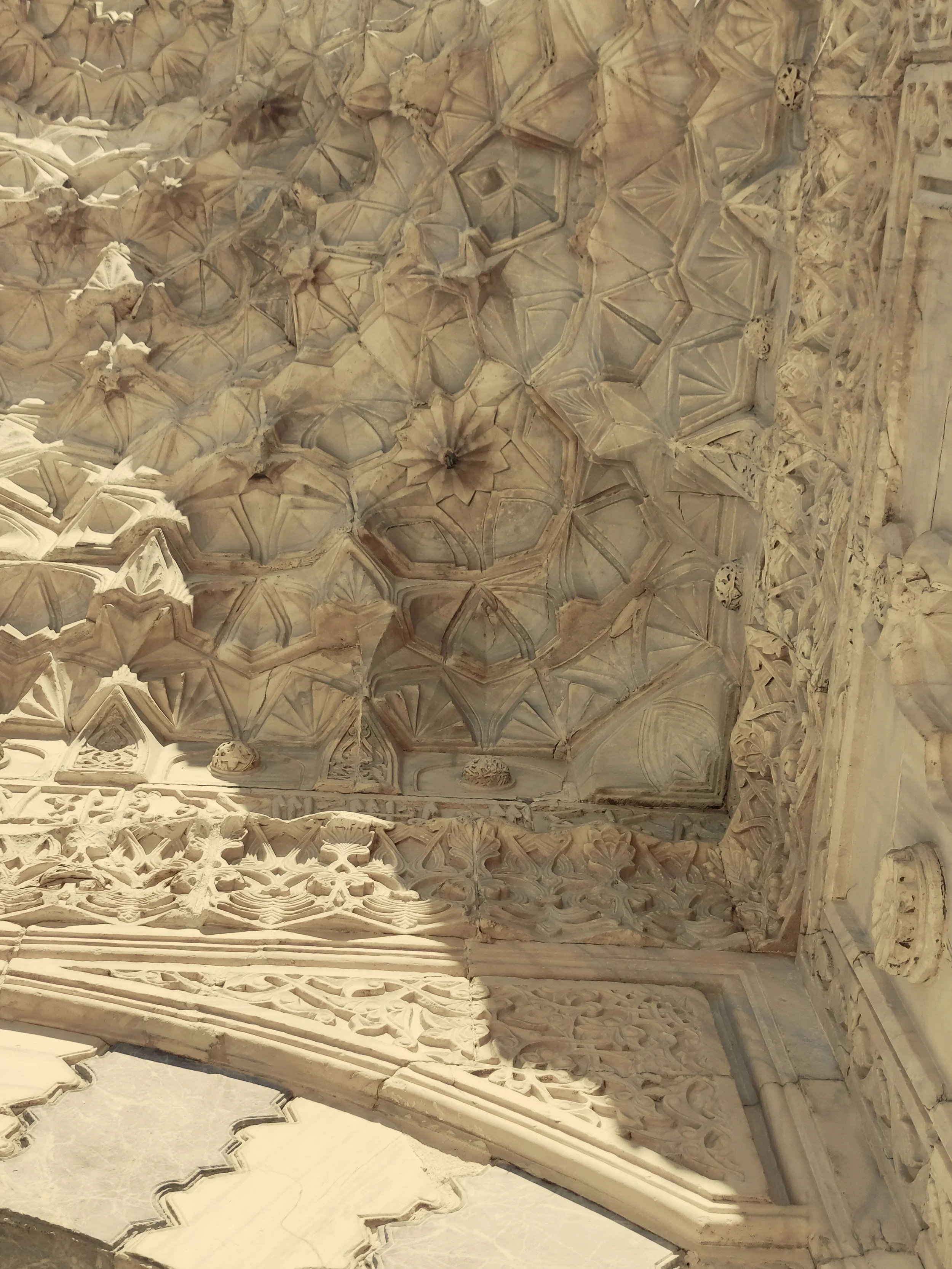 Close-up of intricate carved stone ceiling with geometric patterns and decorative elements.