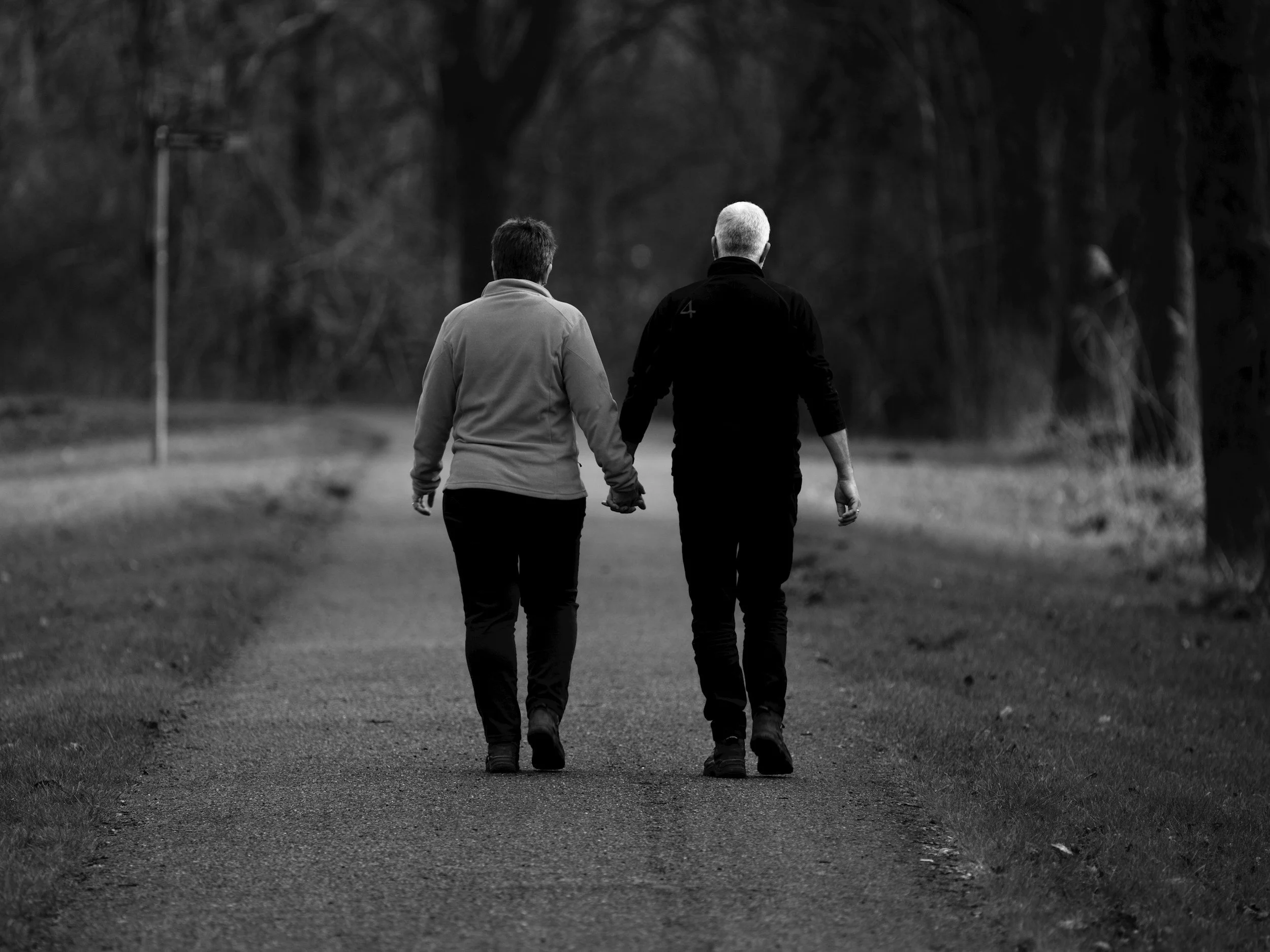 An older couple walking hand in hand along a path