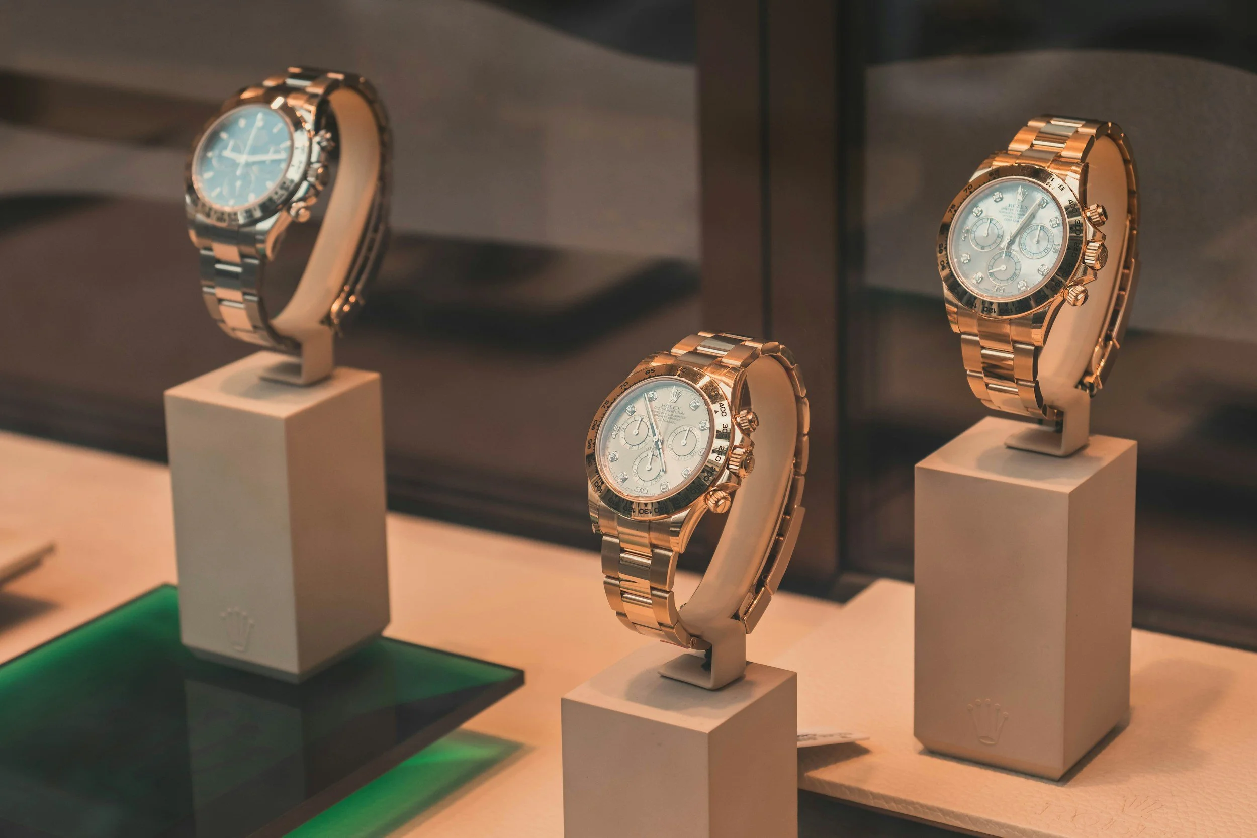 Display of luxury gold and silver wristwatches on white stands inside a showcase.